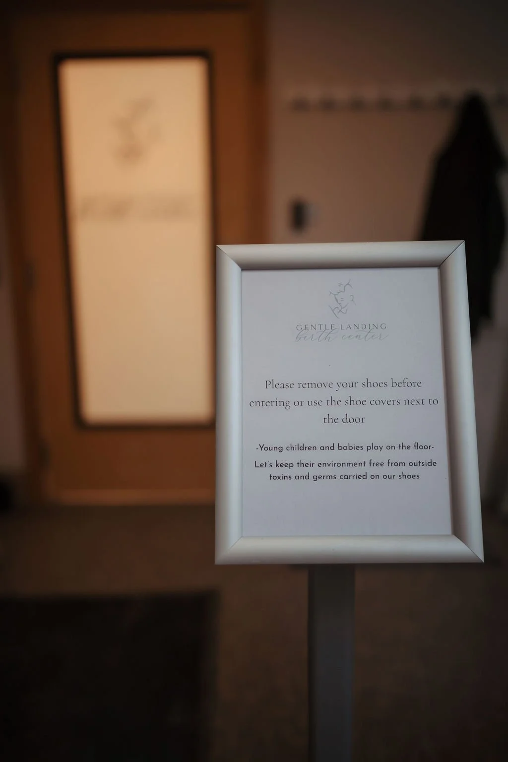 Sign instructing visitors to remove shoes before entering or use shoe covers, with additional notes on children and germs.