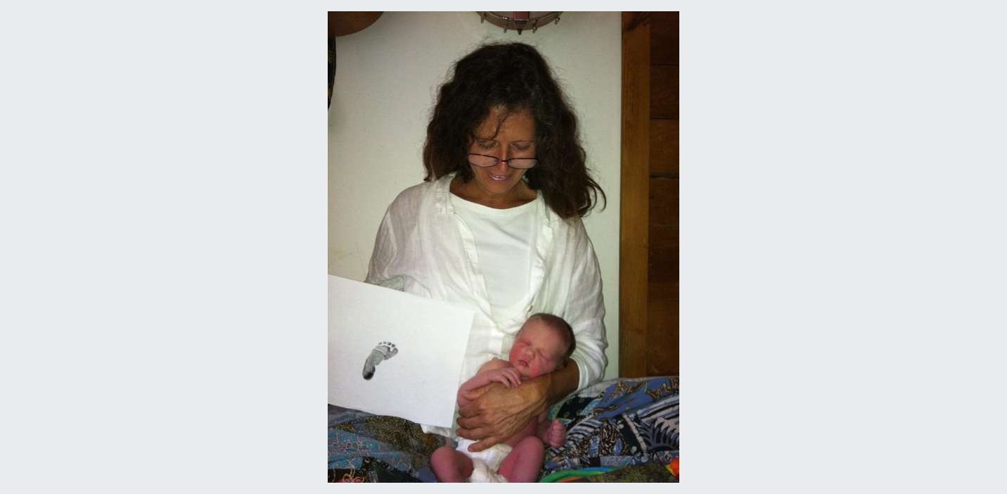 Woman wearing glasses holding a newborn baby in her arms