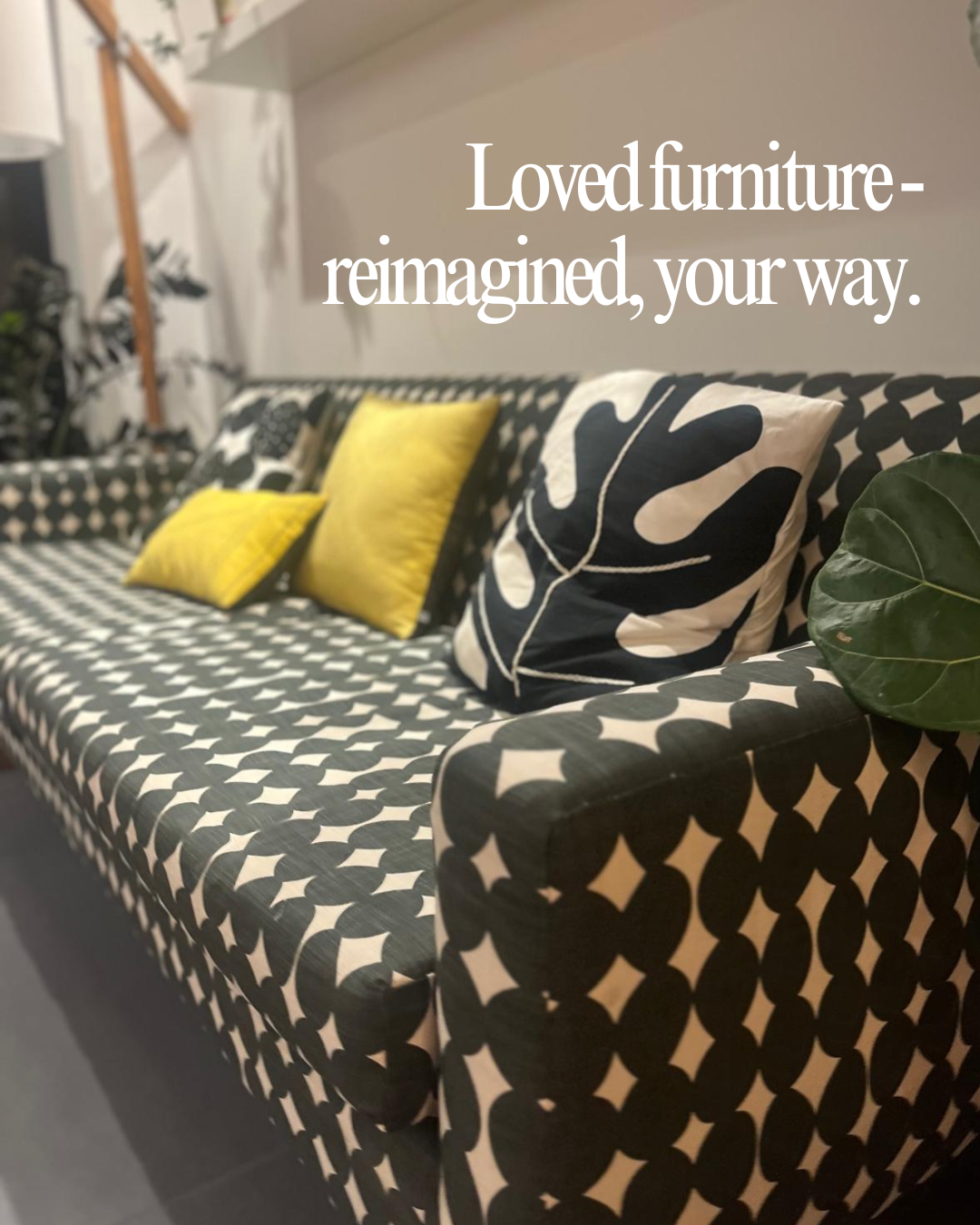 A black and white patterned couch with multiple cushions, including yellow and black and white leafy designs, and a green leaf plant on the armrest. Text overlay states, "Loved furniture-reimagined, your way."