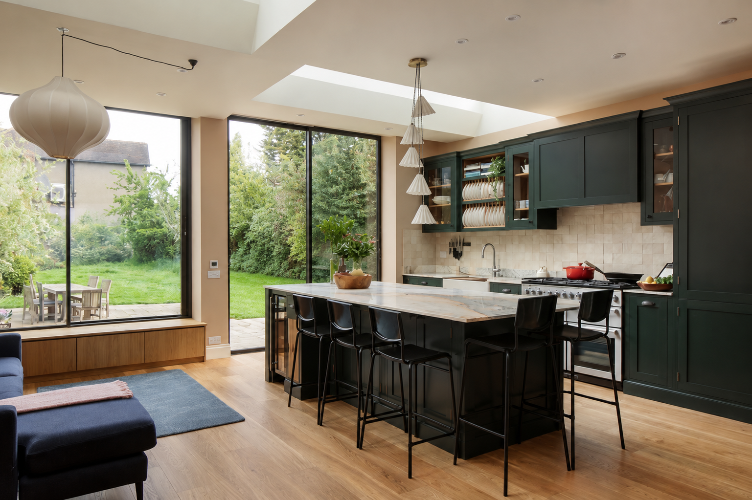 Modern kitchen with black cabinets, white marble island, large windows looking out to green backyard, wooden flooring, and minimalist decor.