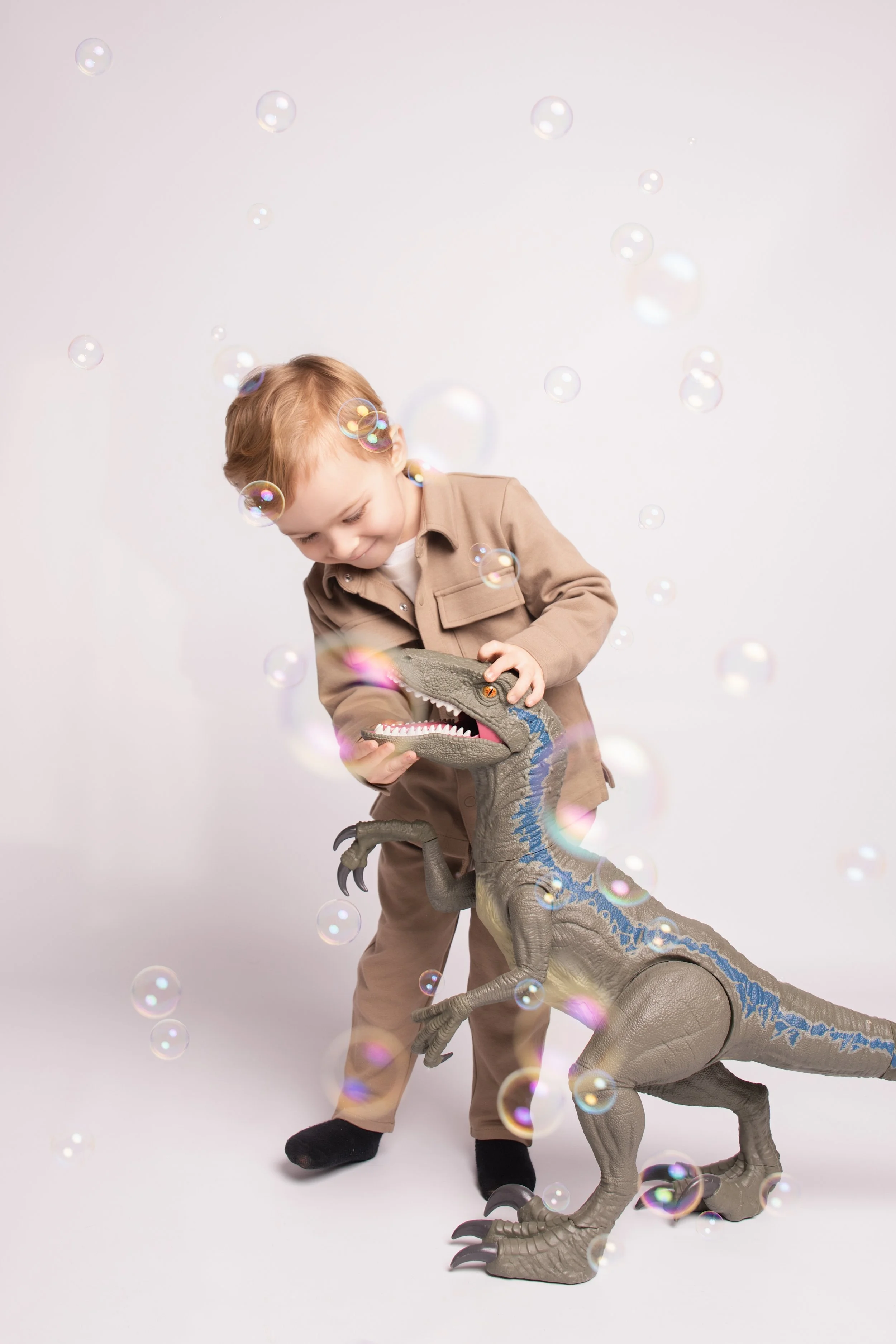 A young girl in a blue dress sitting on the stage floor with her knees drawn up to her chest, looking down thoughtfully.