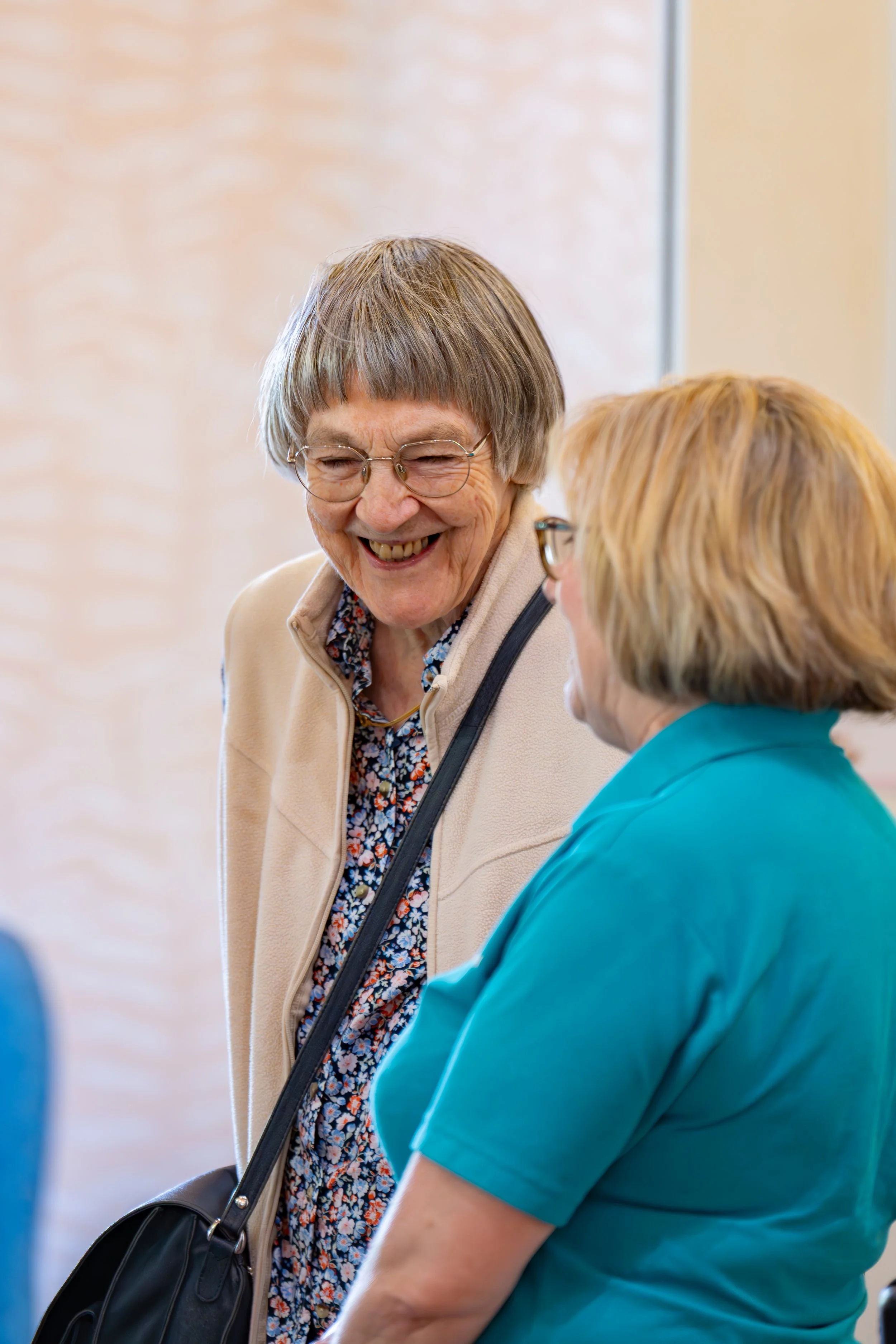 older lady smiling whilst talking to another lady 
