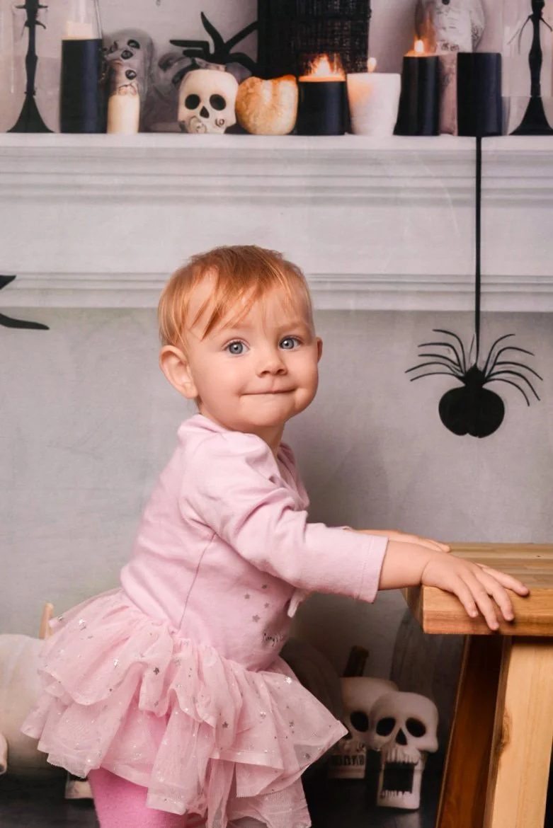 a-little-girl-in-a-pink-dress-sitting-on-a-wooden-table.jpg