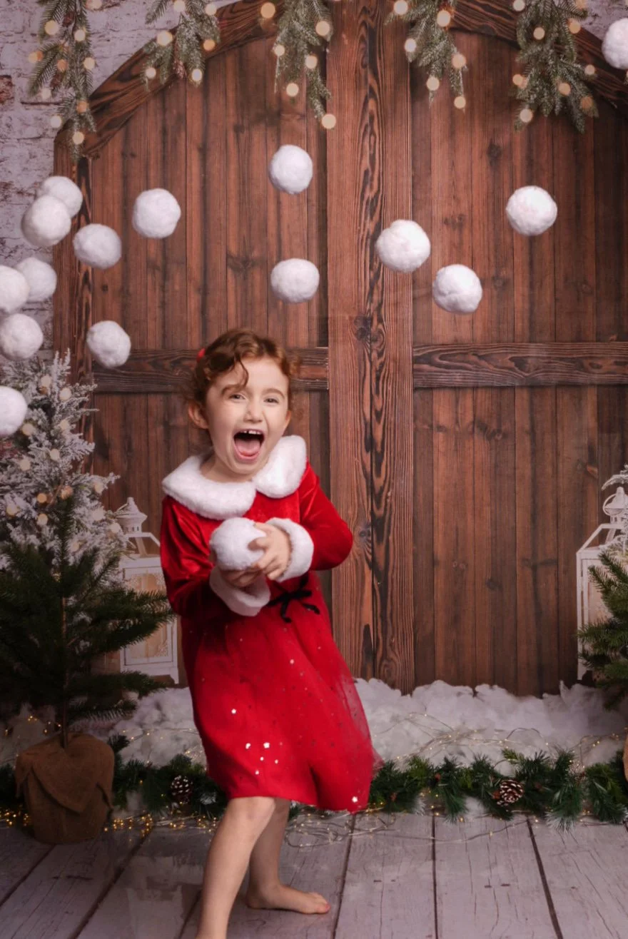 a-little-girl-in-a-red-dress-and-white-fur-coat-is-standing-in-front-of-a.jpg