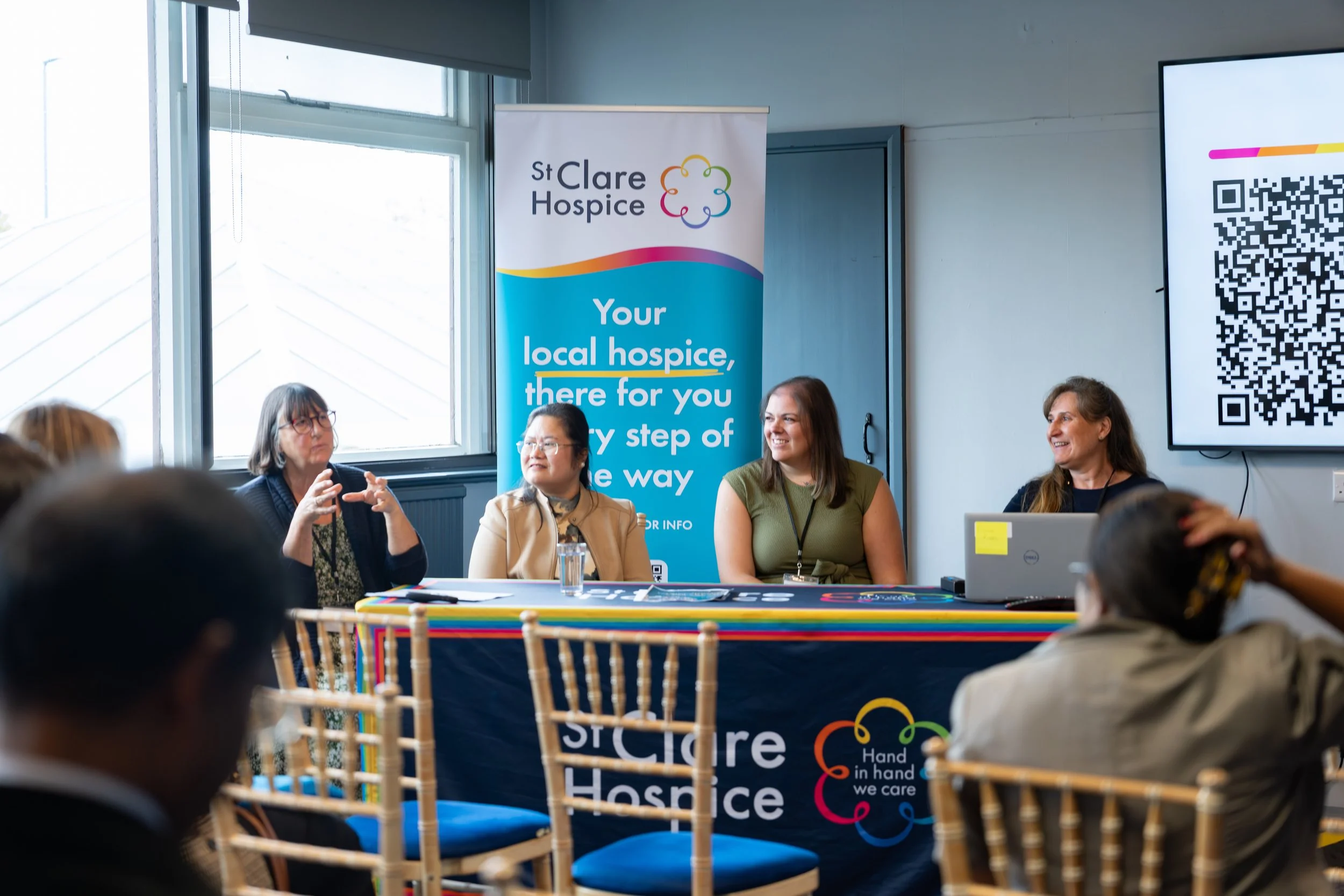 Two women in colorful dance costumes performing on stage, one in a yellow outfit with a pleated skirt and the other in a pink outfit with a matching skirt, under stage lights.