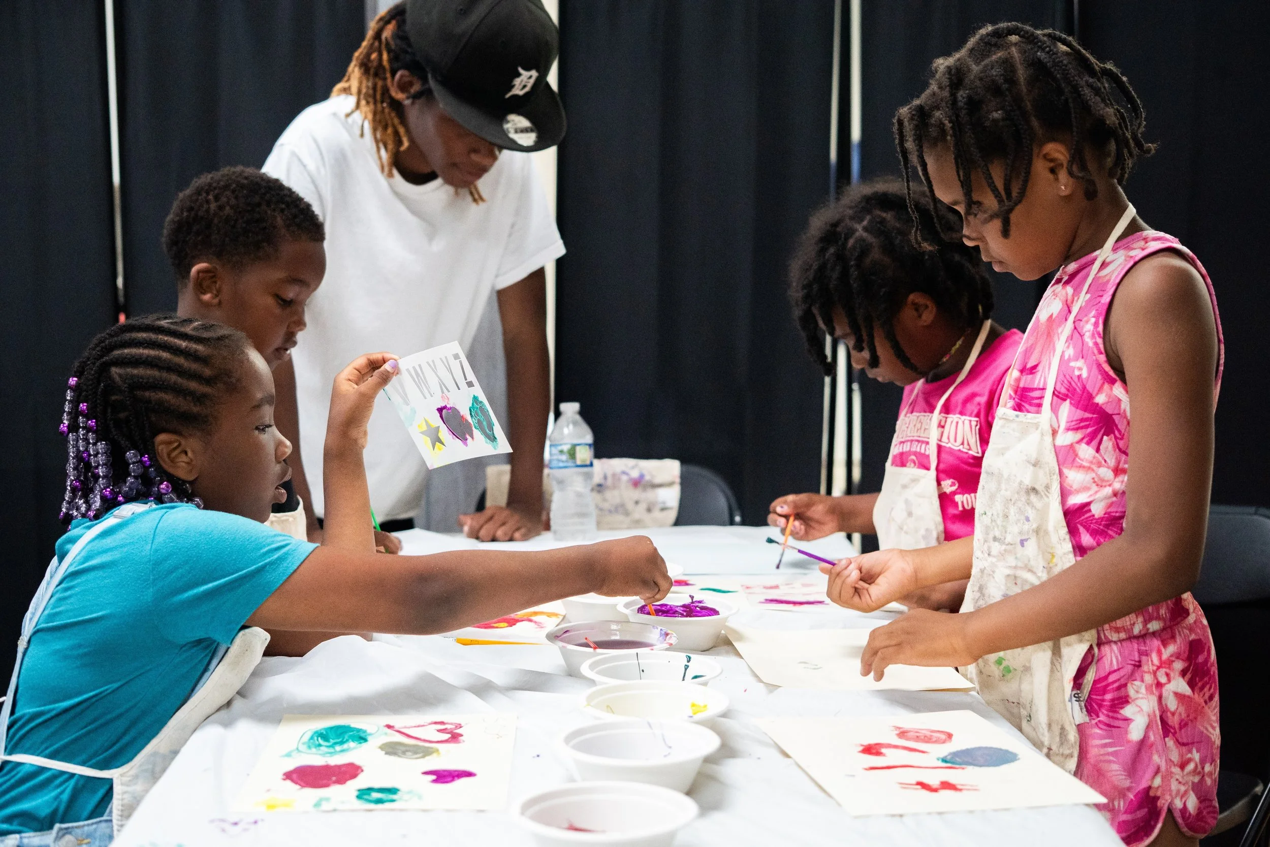 Children painting at a table with adult supervising