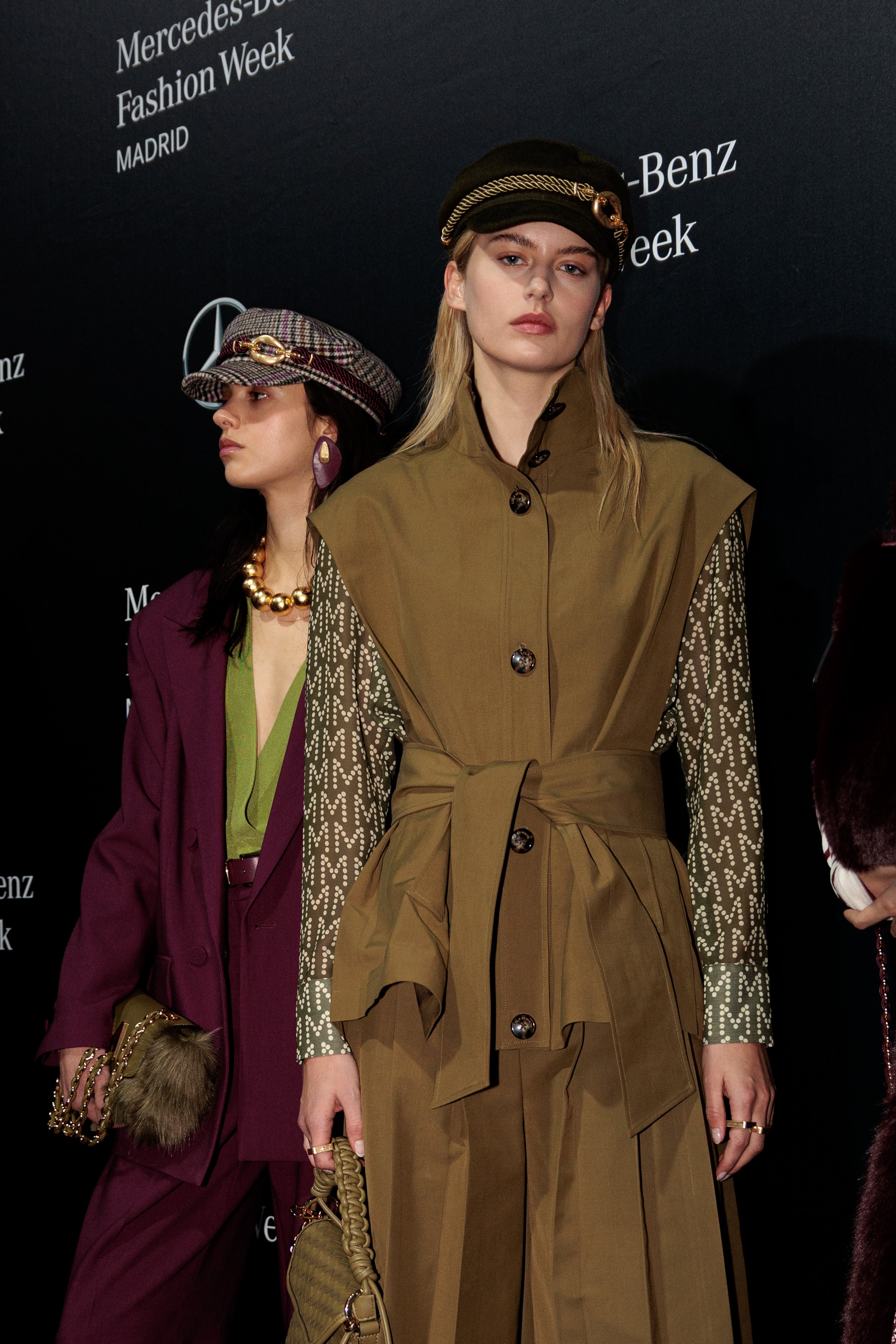 Dos modelos en pasarela durante la Semana de la Moda de Mercedes-Benz en Madrid, usando ropa de diseño de lujo con accesorios llamativos.