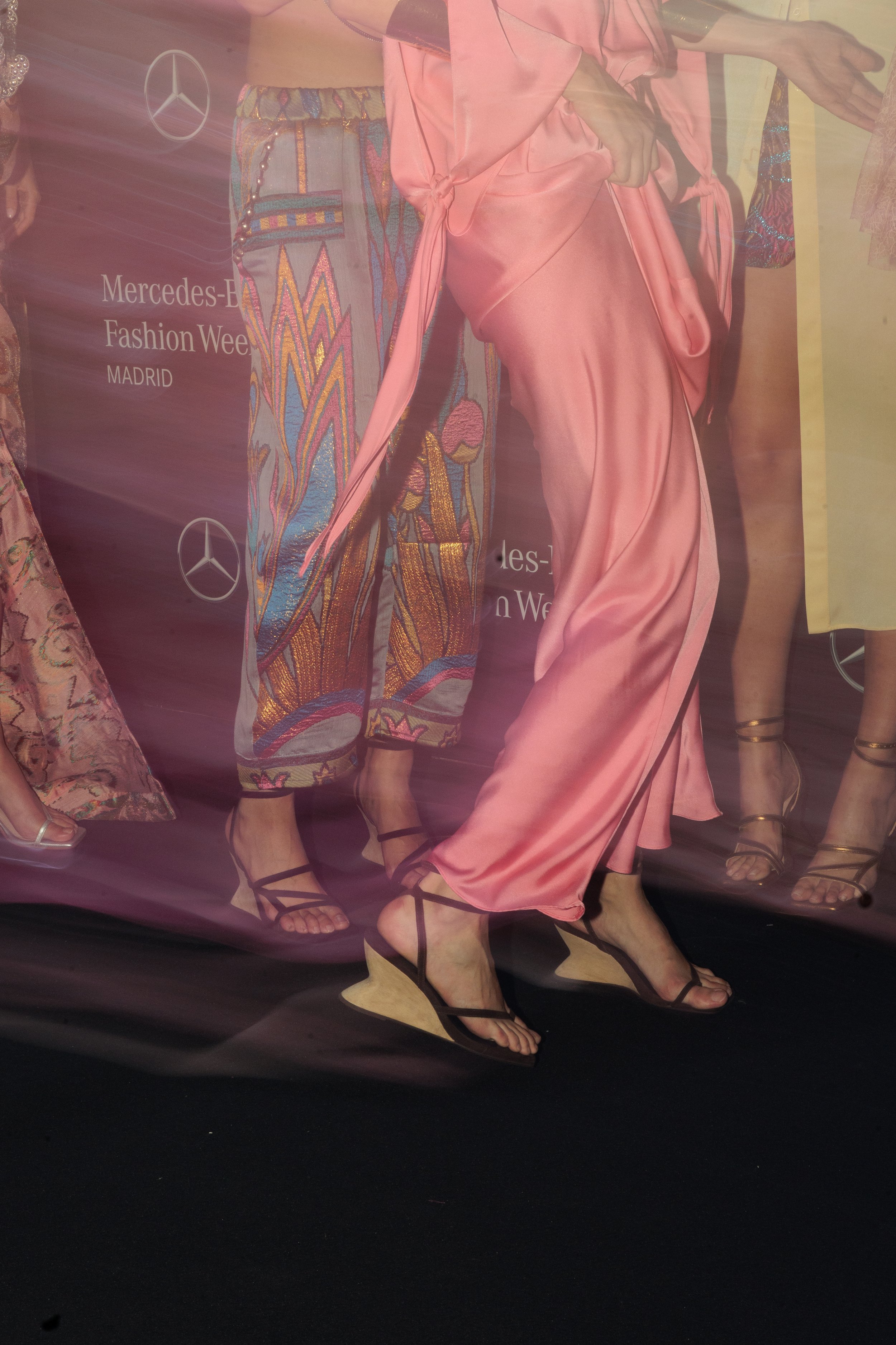 Modelos posando en un desfile de moda en Madrid, vistiendo prendas de colores brillantes y calzado elegante.