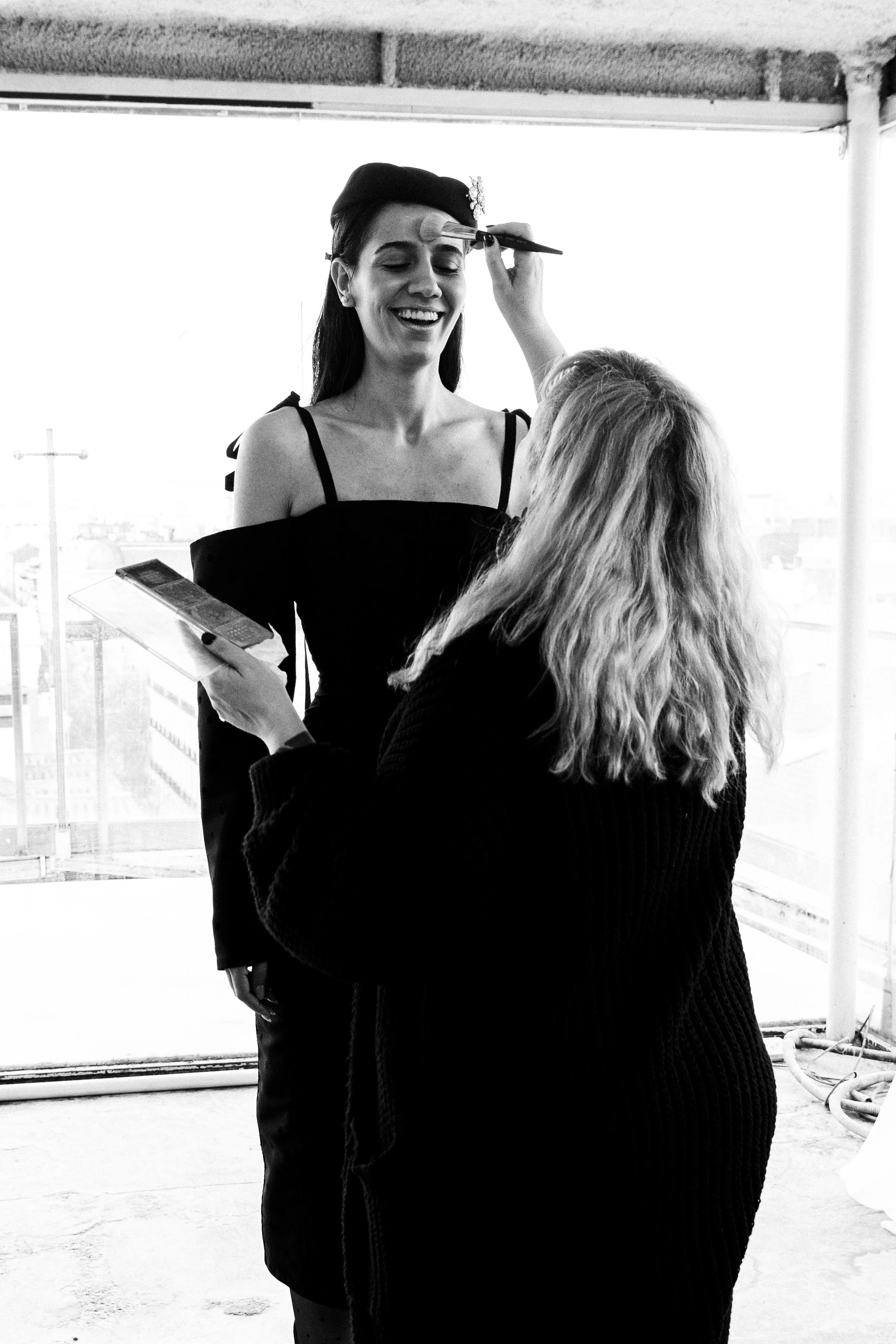 Una mujer recibe maquillaje de una artista en un espacio abierto