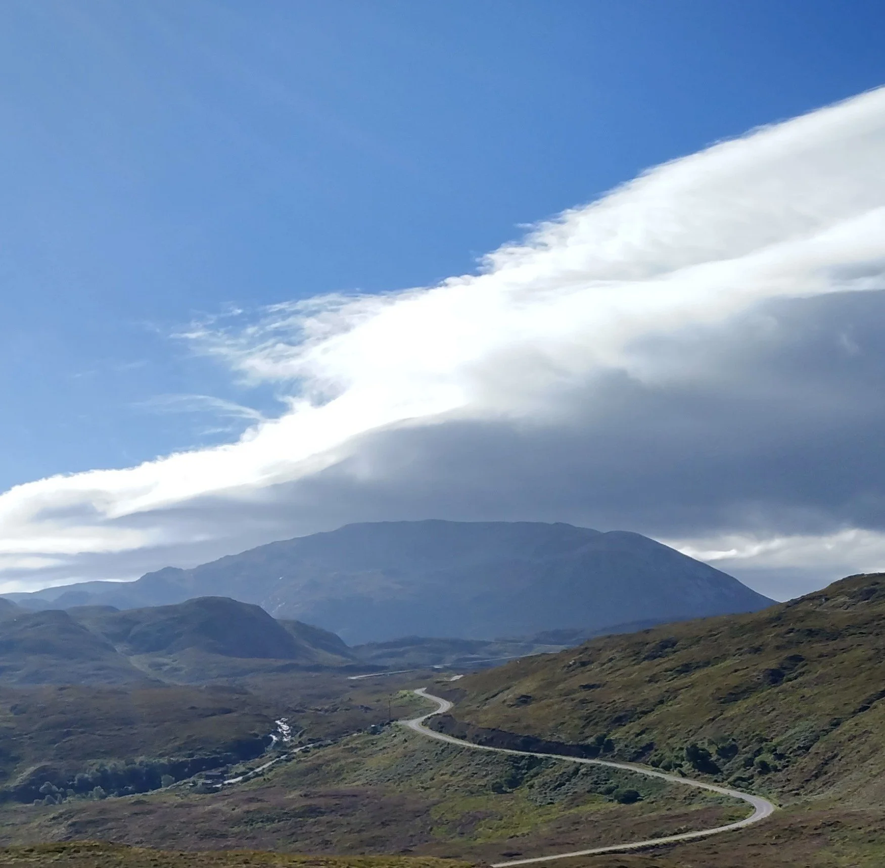A scenic view of mountain landscape with a winding road - part of the NC500.