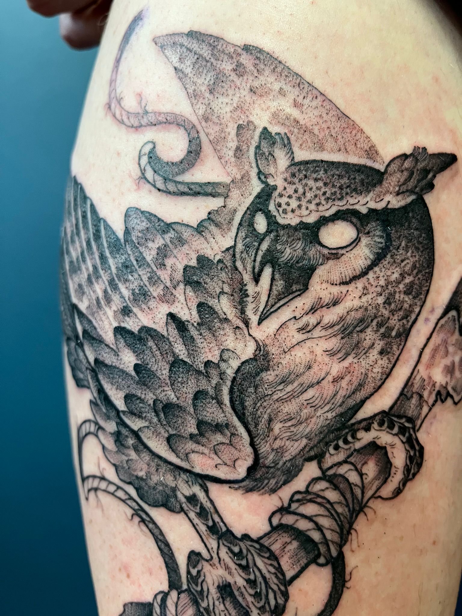 A black and gray tattoo of an owl, perched on a branch.
