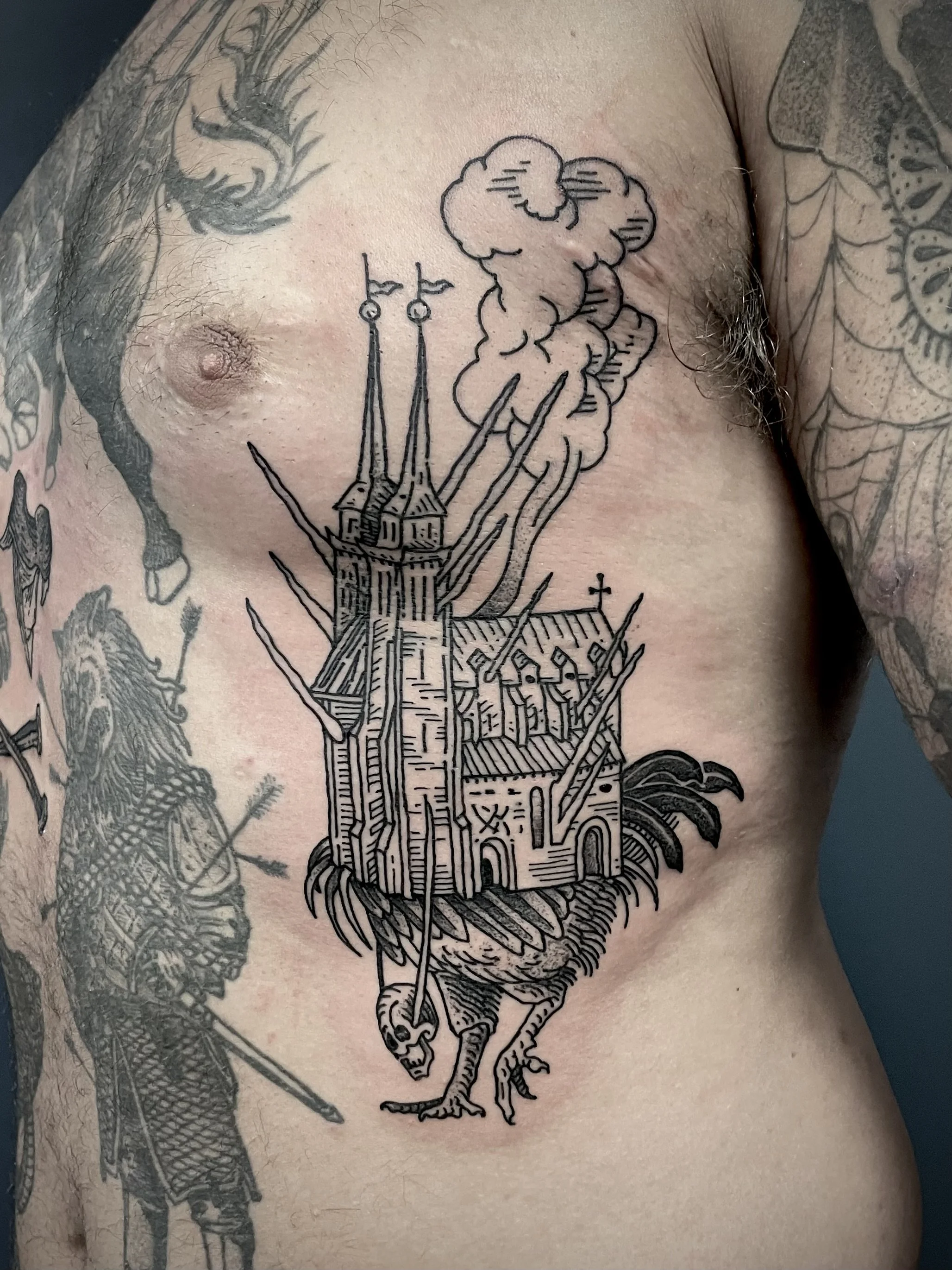 Tattoo of a castle with spikes and a rooster's head on the lower part of the design, with smoke rising from the castle.