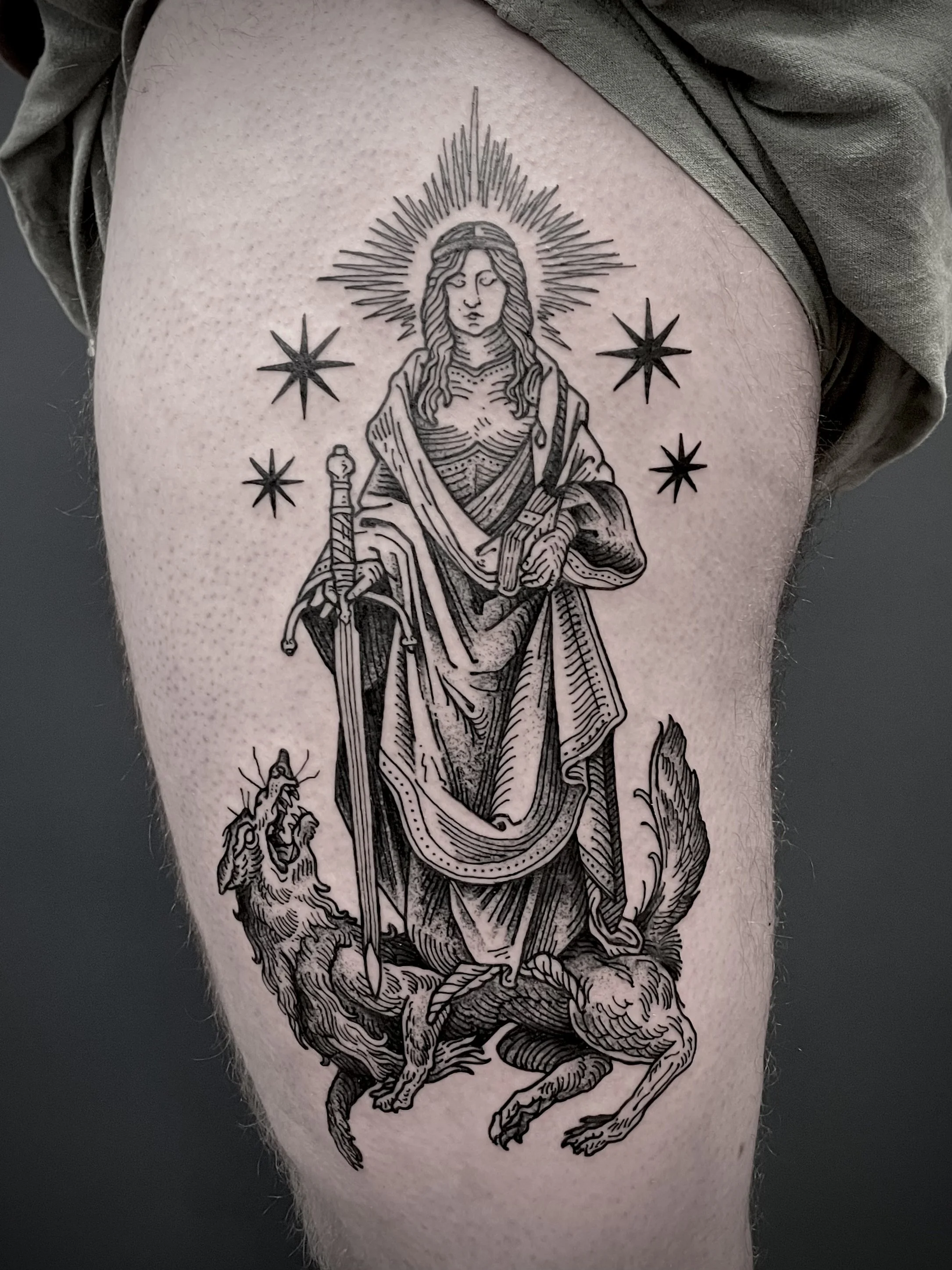 Tattoo of a religious figure, likely Saint Mary, standing on a wolf with a halo and surrounded by stars.