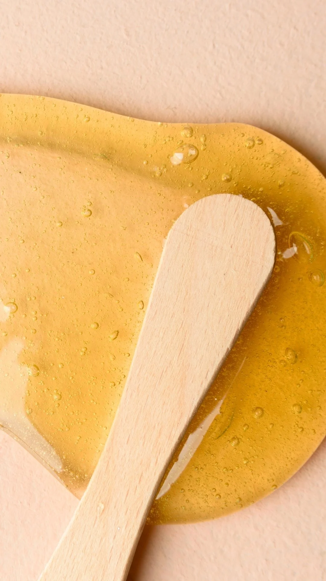 Un bâtonnet en bois posé sur une surface de gélatine à couleur jaune, avec des bulles d'air visibles dans la gélatine.