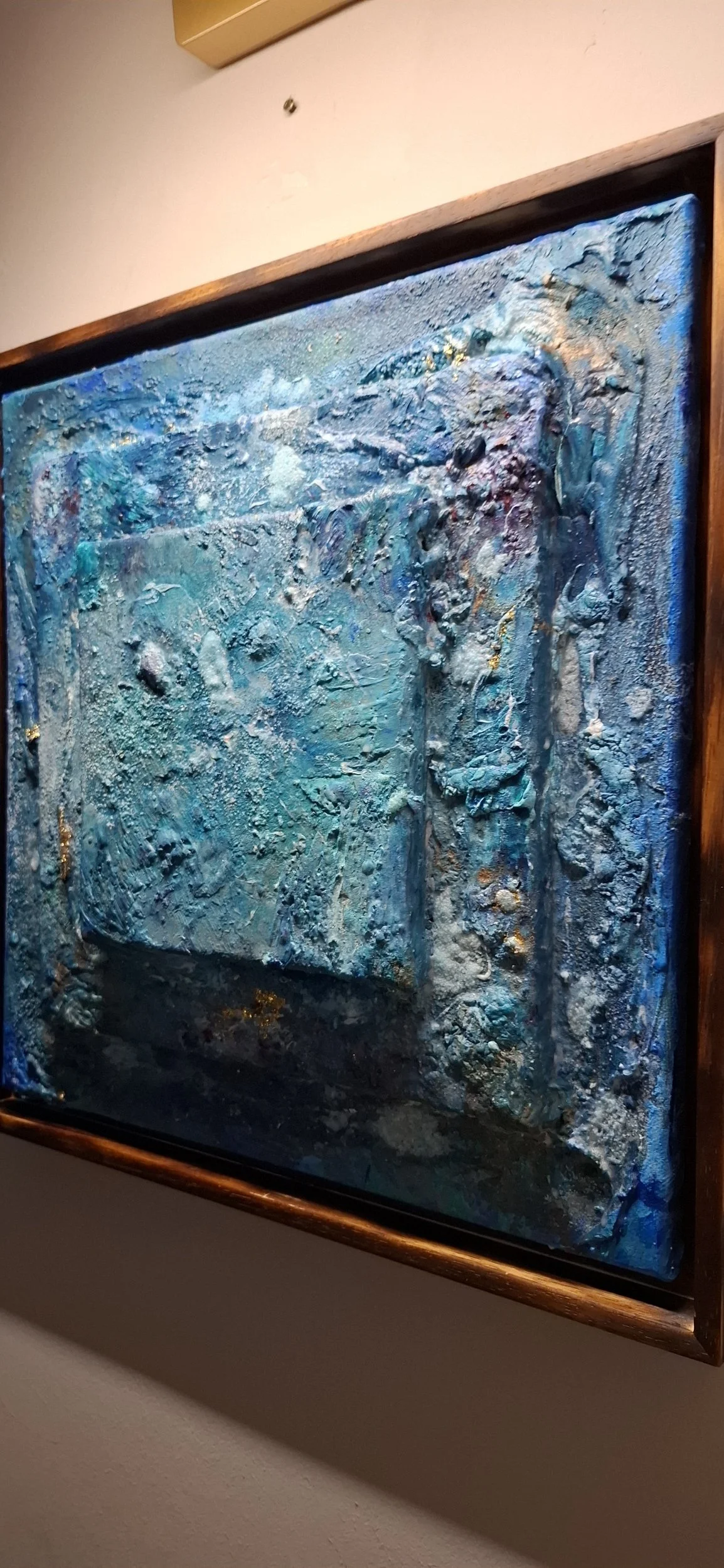 Abstraktes Gemälde mit strukturierter, blauer und silberner Farbgestaltung in einem Holzrahmen.