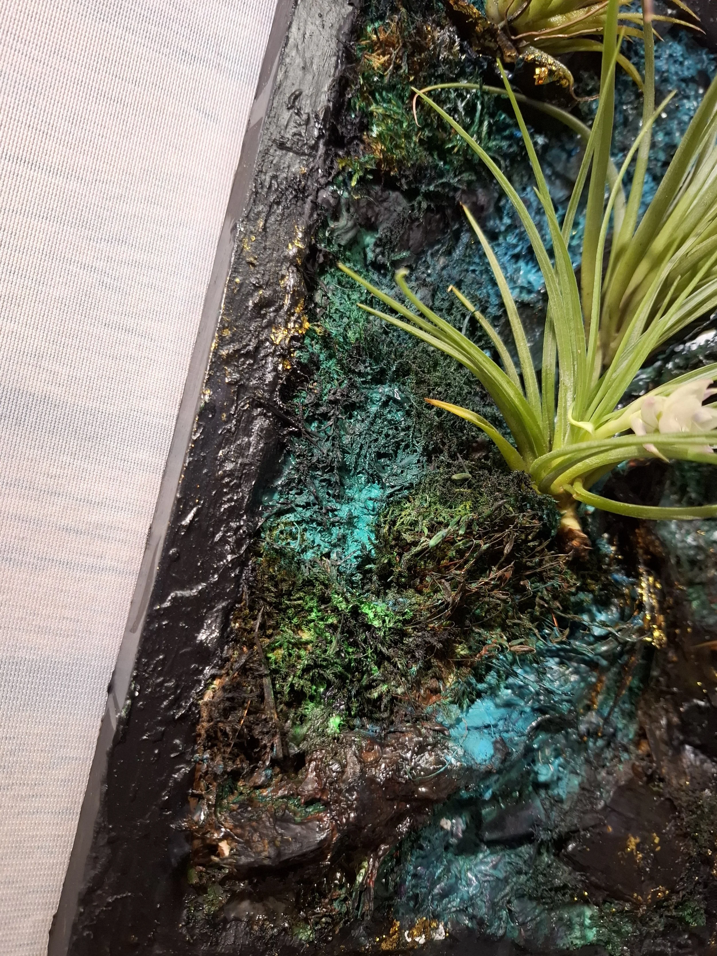 Kunstpflanzen mit grüner Pflanze in einer künstlichen, moosbedeckten Umgebung, beleuchtet mit bunten Lichtern.