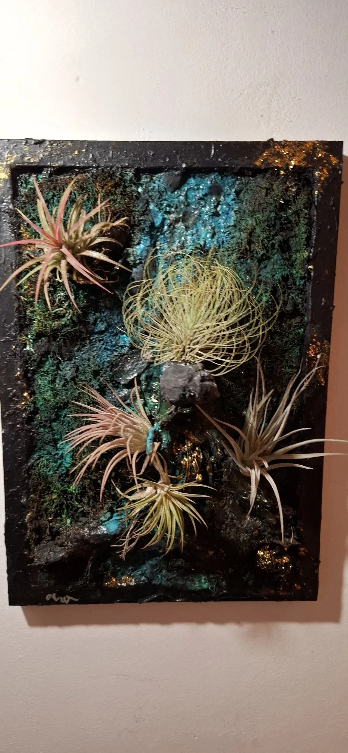 Kunstwerk mit Trockepflanzen, bunten Lichtern und dunklem Hintergrund.