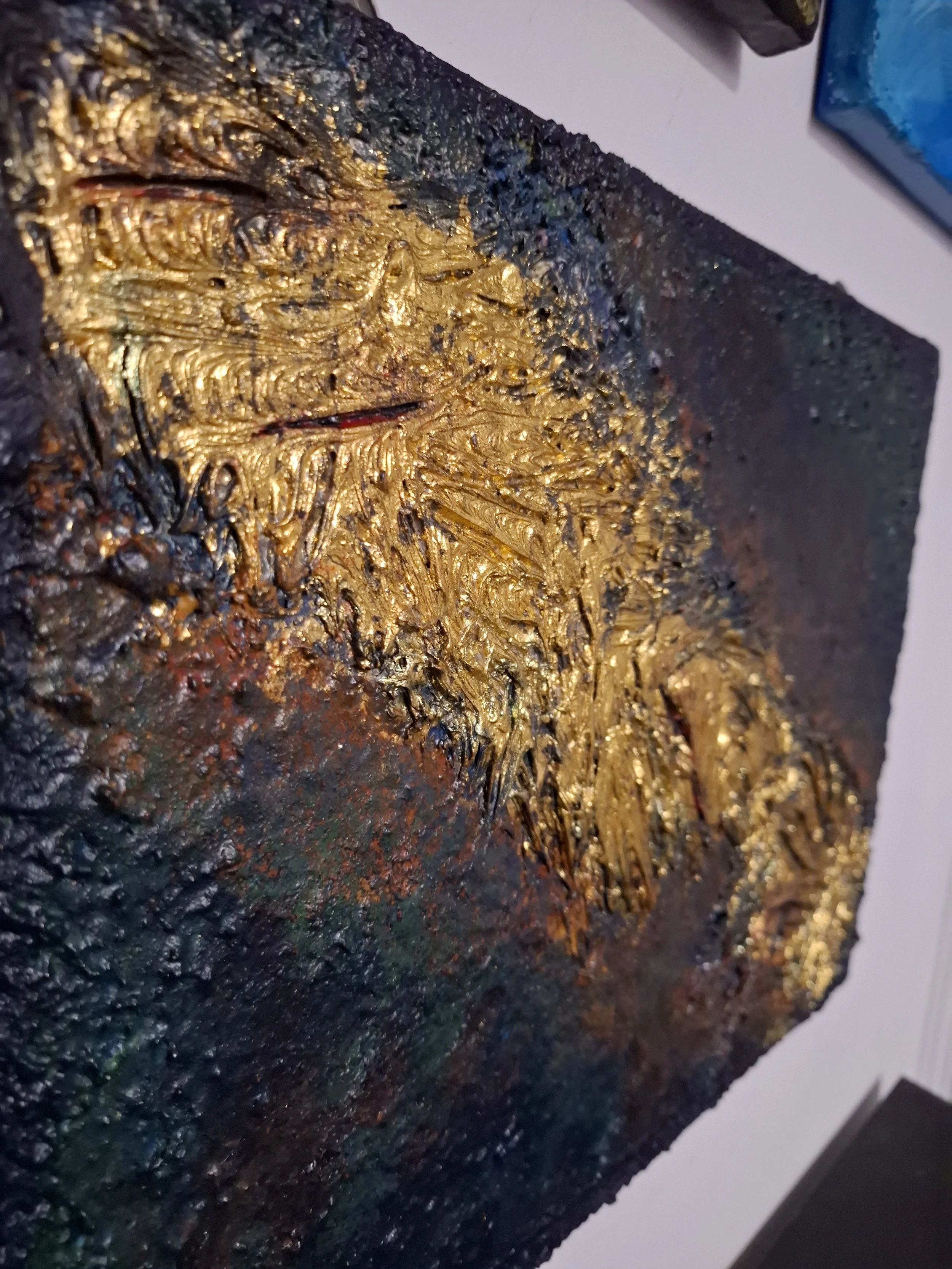 Ein abstraktes Gemälde mit goldfarbenen, strukturierten Elementen auf dunklem Hintergrund.