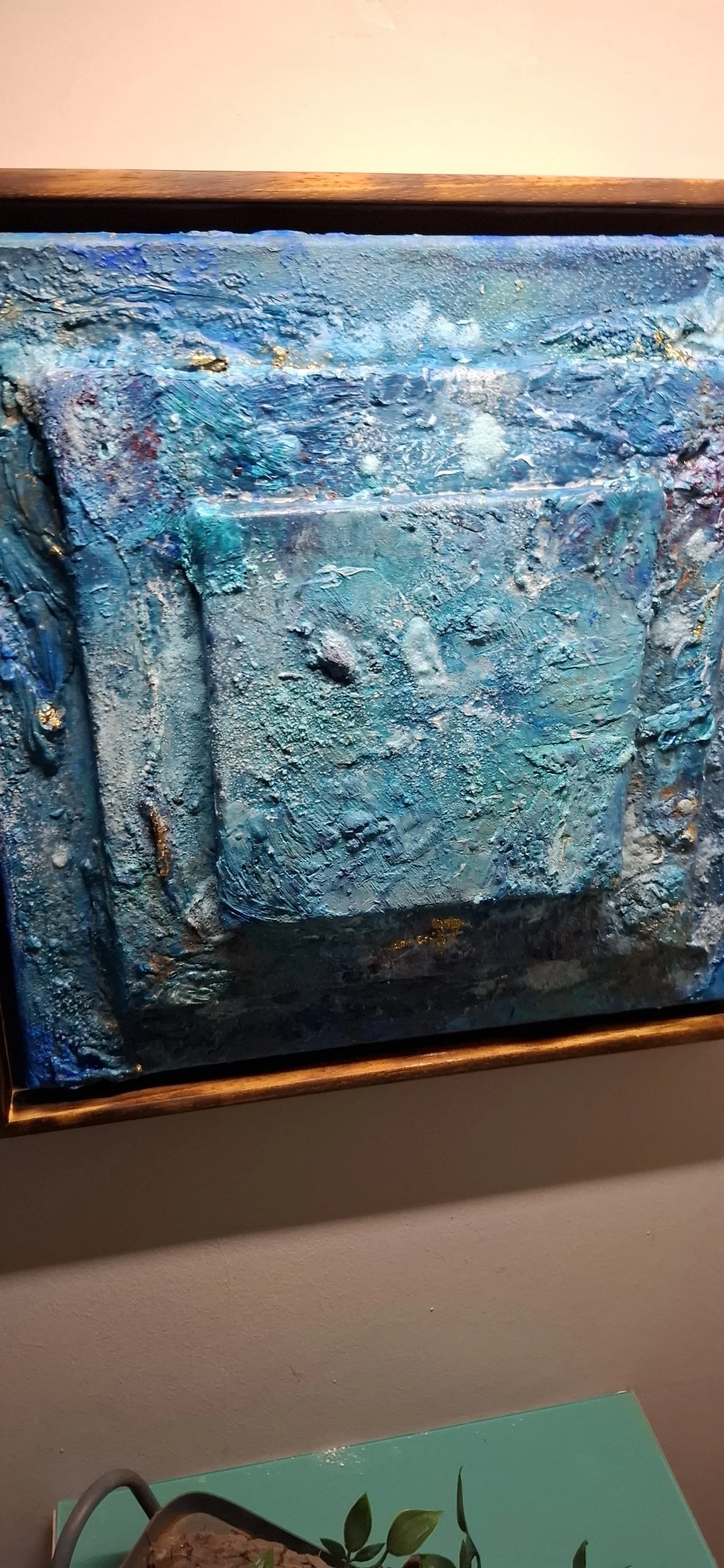 Abstraktes Gemälde mit blauen, türkisfarbenen und weißen Texturen, in eine Goldlinie eingefasst.