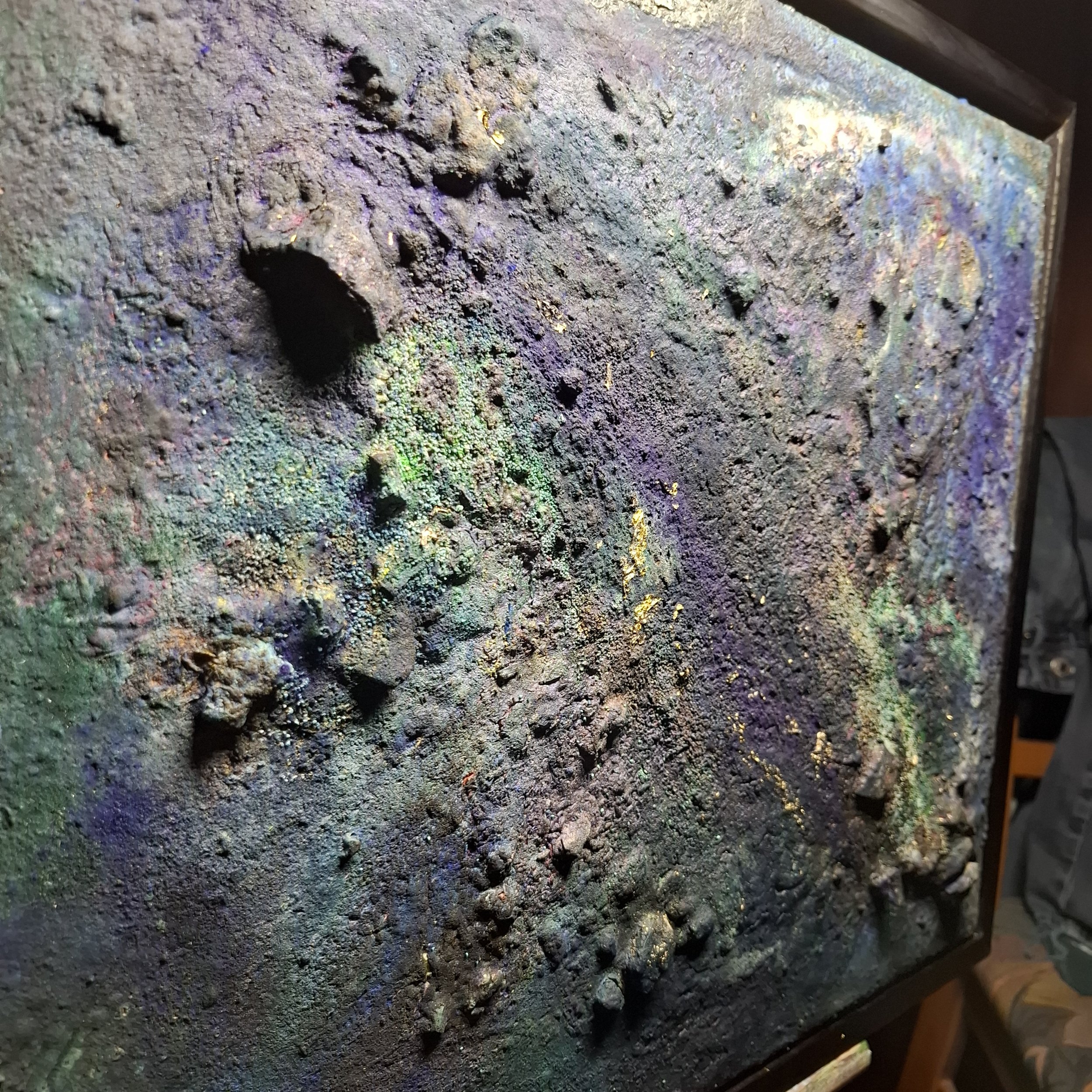 Eine strukturierte, mit bunten Farben bemalte Oberfläche mit mehreren kleinen Vertiefungen und Höhlen.