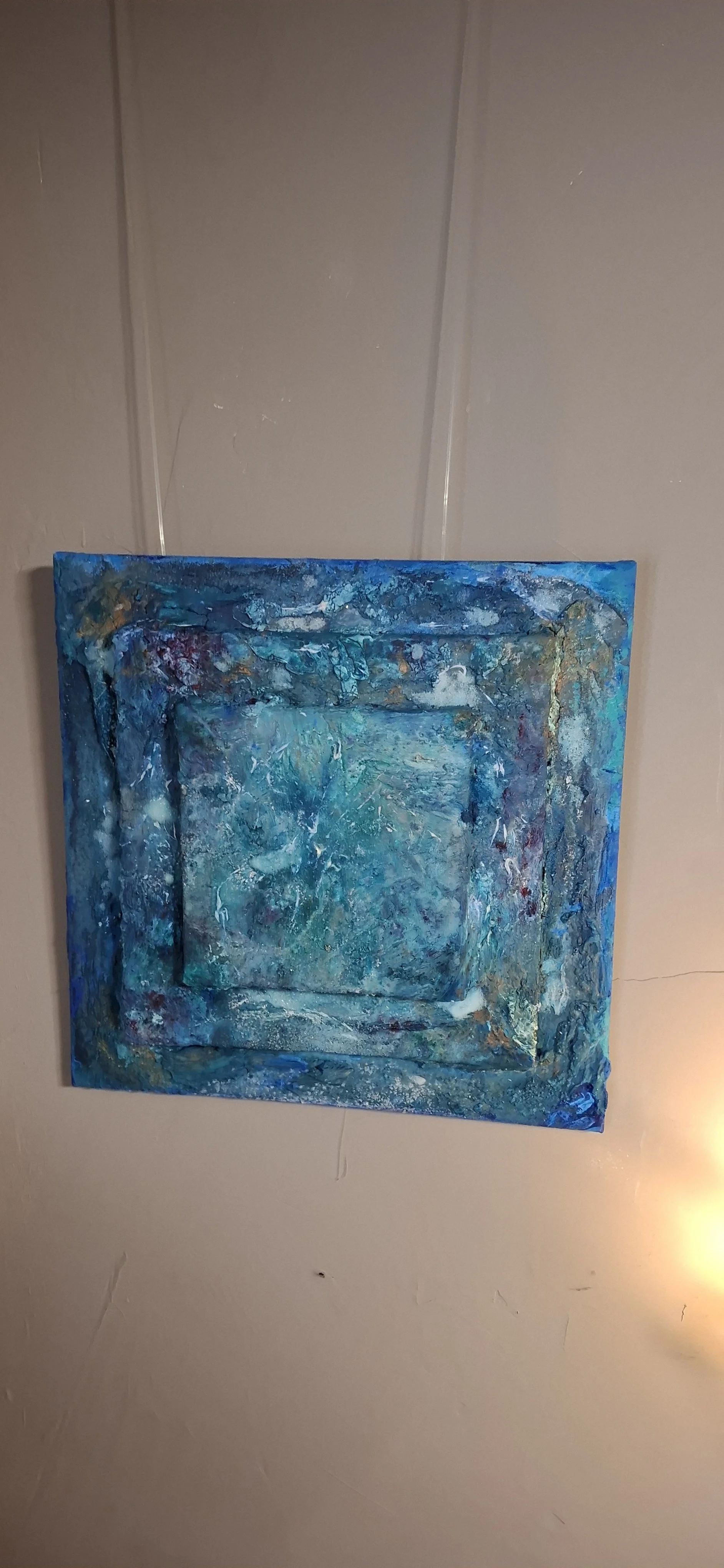 Abstraktes, blau gehaltenes Gemälde an einer Wand aufgehängt.