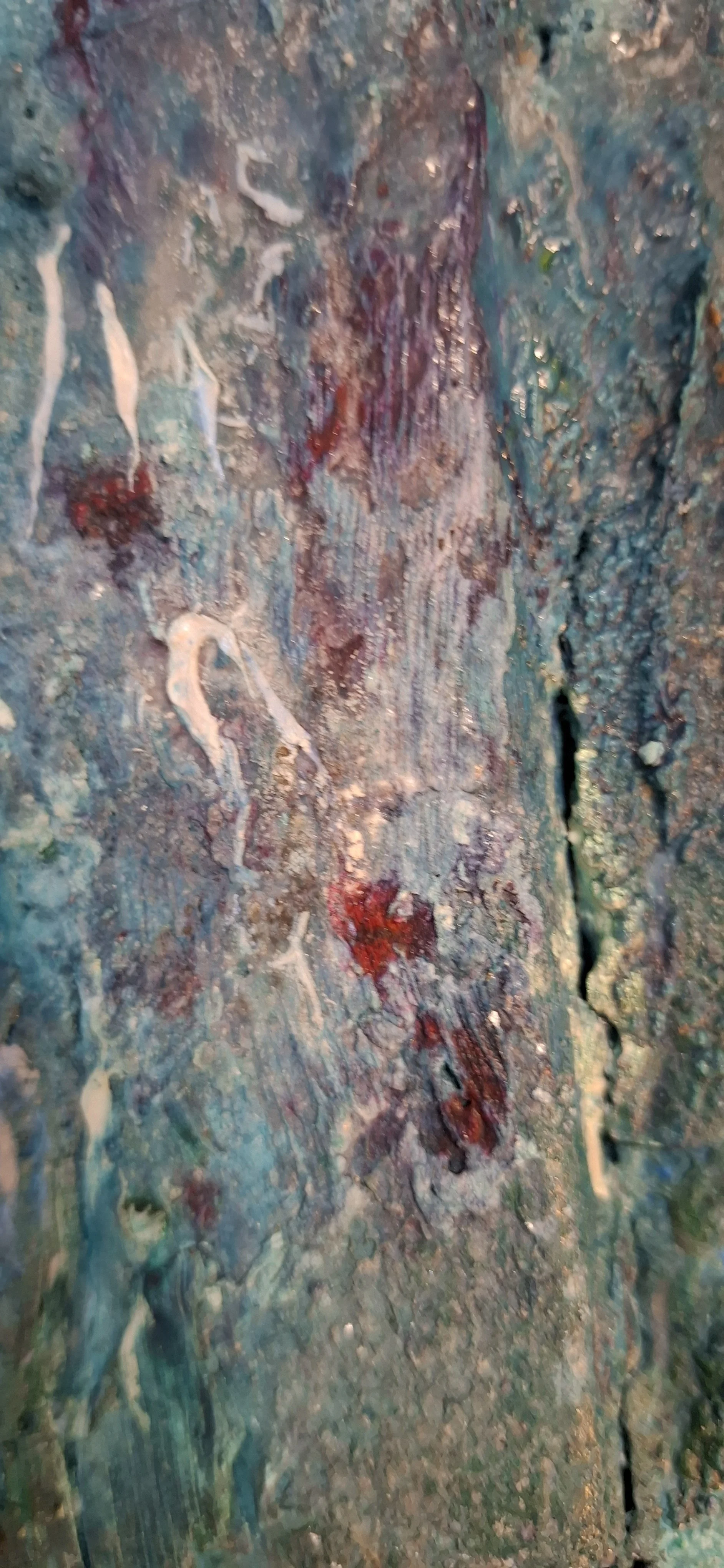 Nahaufnahme einer bemalten, strukturierten Holzoberfläche mit verschiedenen Farben und Texturen.