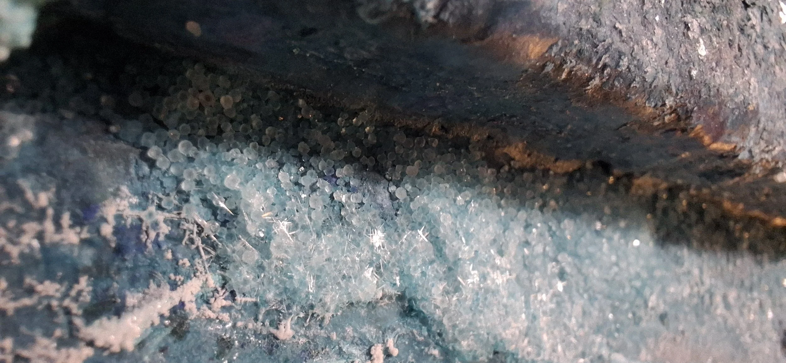 Nahaufnahme von Eiskristallen auf einer eisigen Oberfläche mit rustikaler, dunkler Hintergrund.