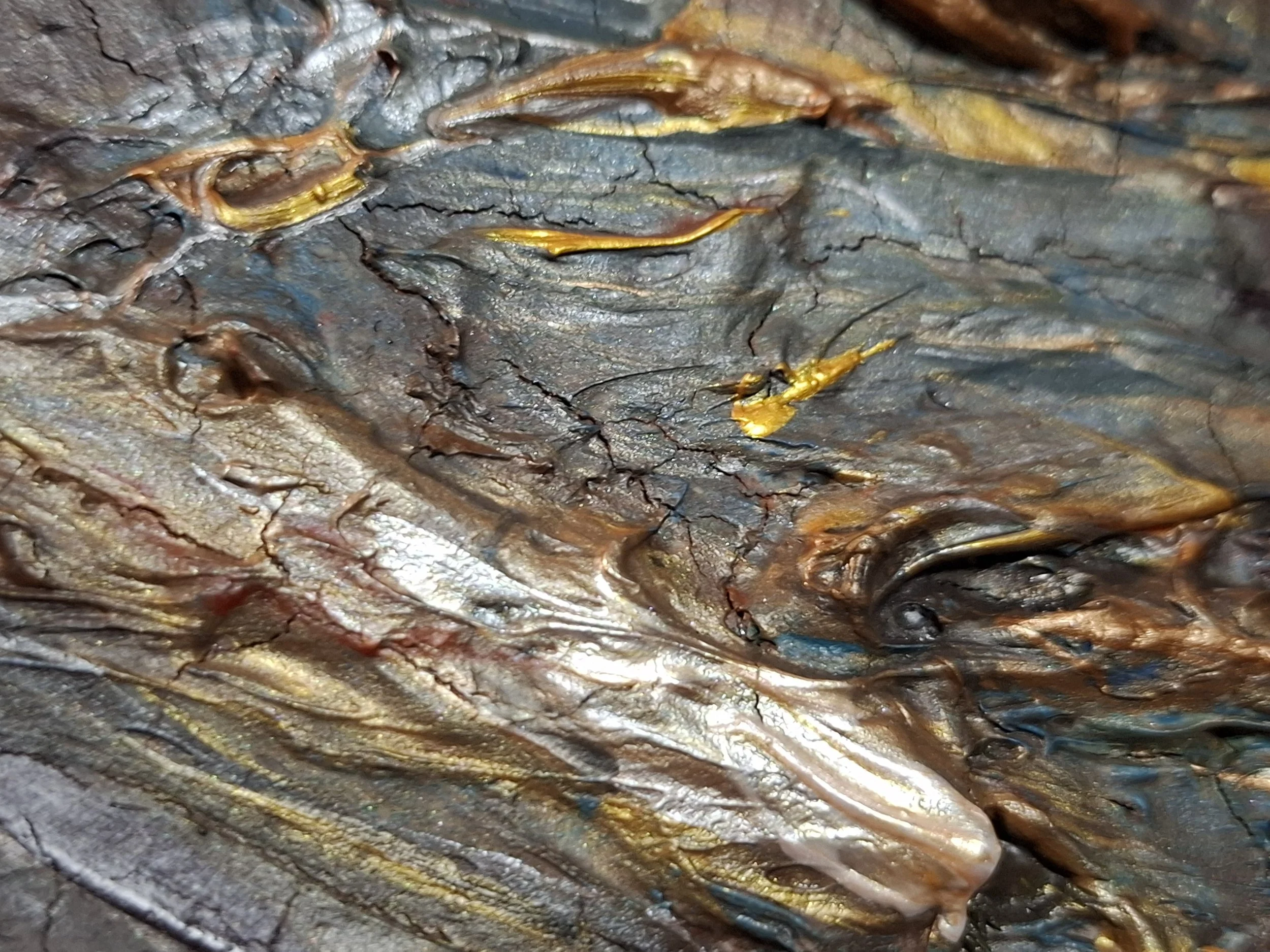 Nahaufnahme einer Textur mit dunklen, rissigen und schimmernden Oberflächen, möglicherweise von Baumrinde oder Metall, mit goldenen und bronzefarbenen Akzenten.