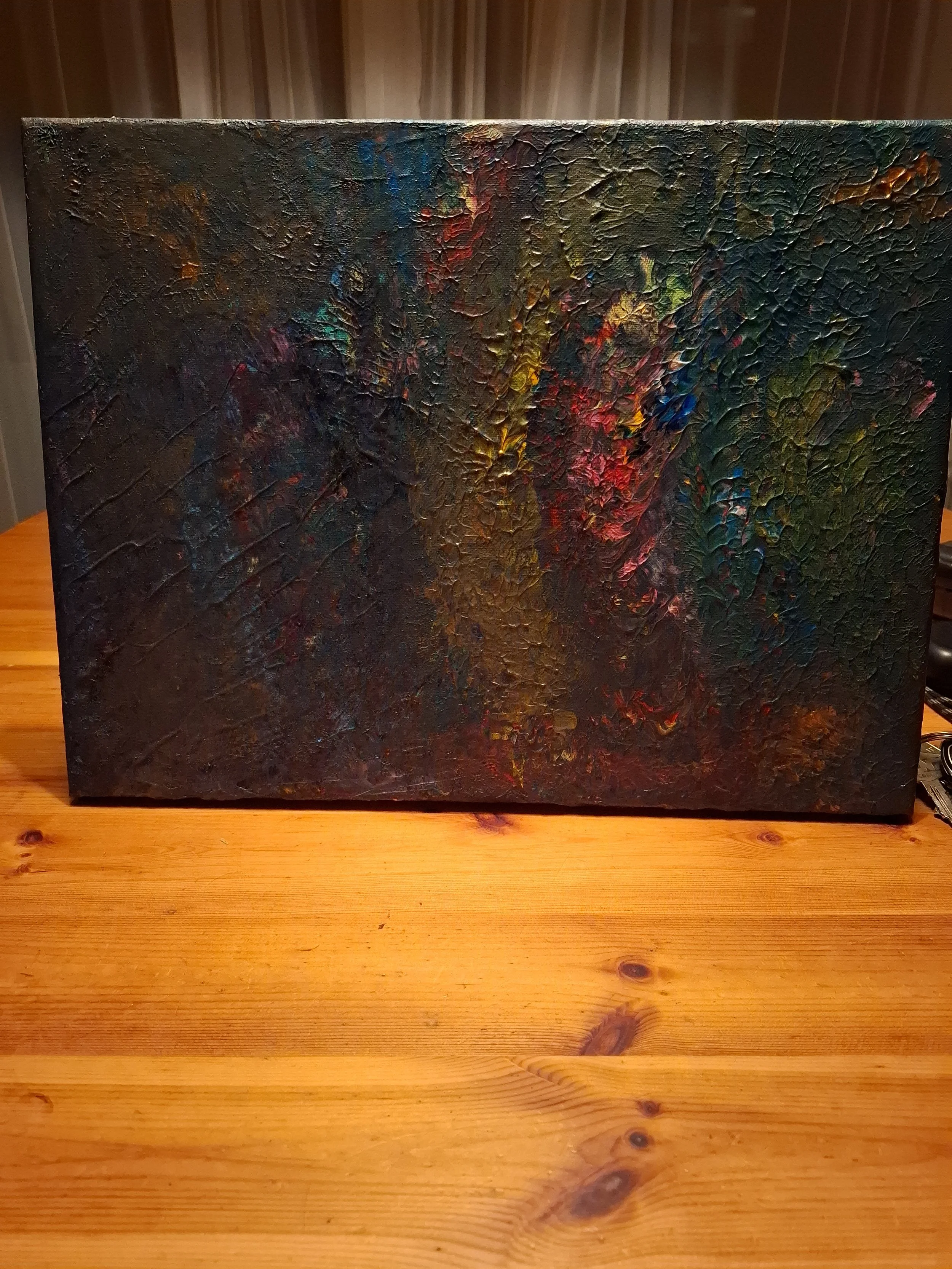 Ein abstraktes Gemälde mit kräftigen, texturierten Pinselstrichen in dunklen und erdigen Farben auf einer Leinwand, die auf einem Holztisch steht.