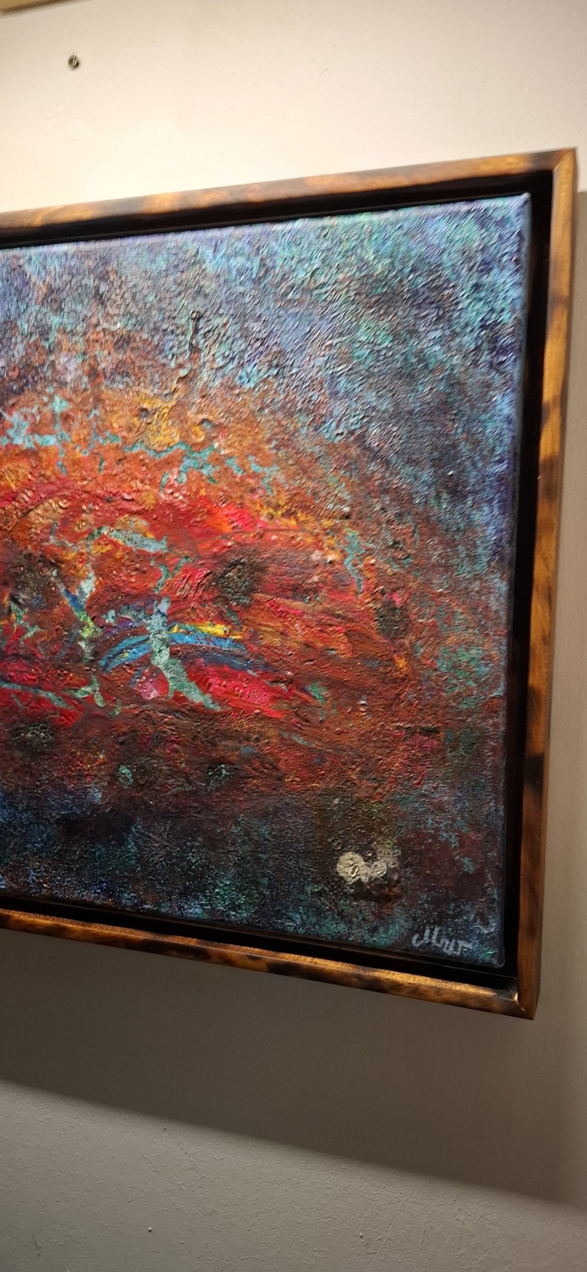 Ein abstraktes Gemälde mit lebendigen, warmen Farben in einem Holzrahmen. Das Kunstwerk zeigt strukturierte, farbige Muster.
