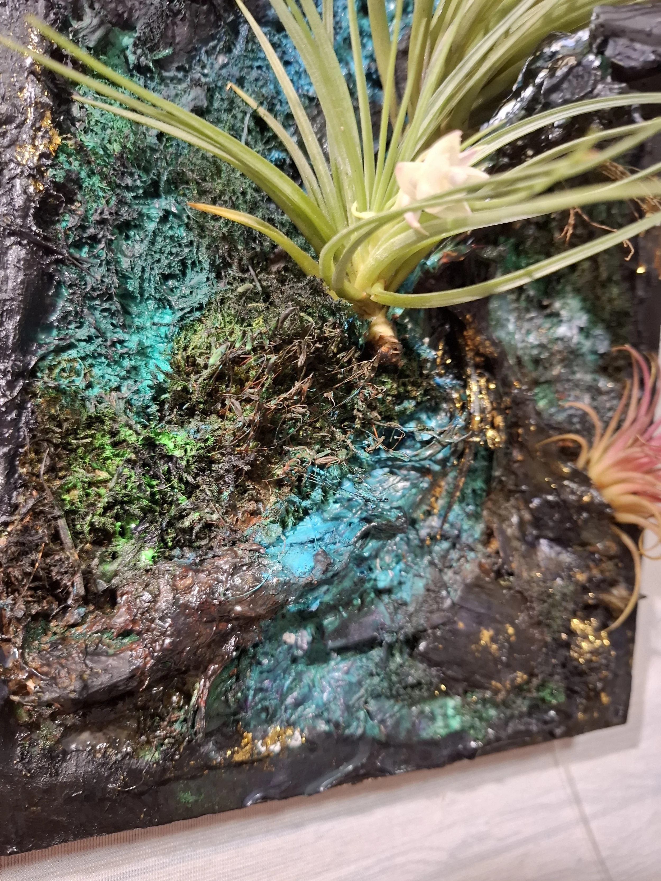 Kunstvoll gestaltete Pflanzen an einer moosbedeckten Wand mit bunten Lichteffekten.