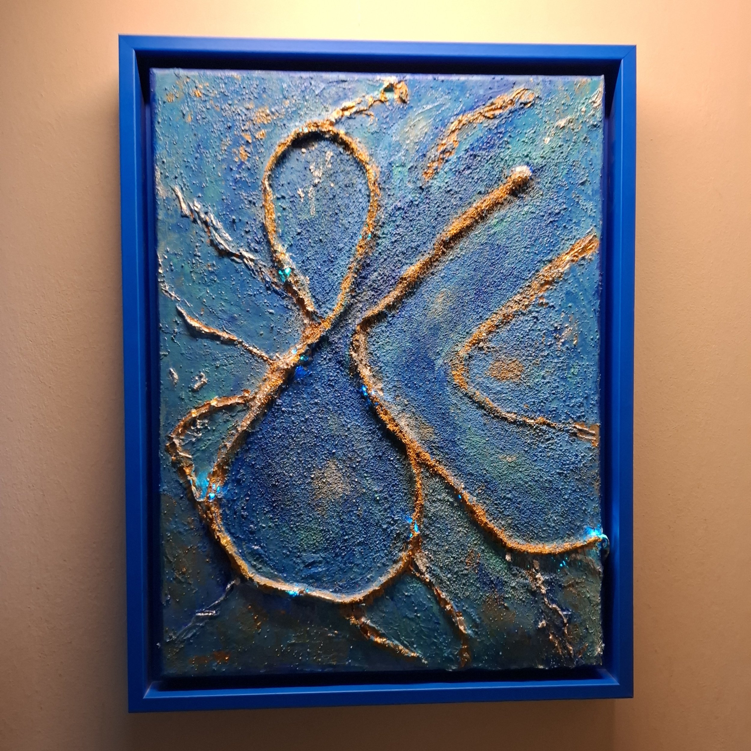 Abstraktes, texturiertes Kunstwerk mit goldenen Linien auf blauer, grüner und türkiser Hintergrund, eingerahmt in einen blauen Rahmen.