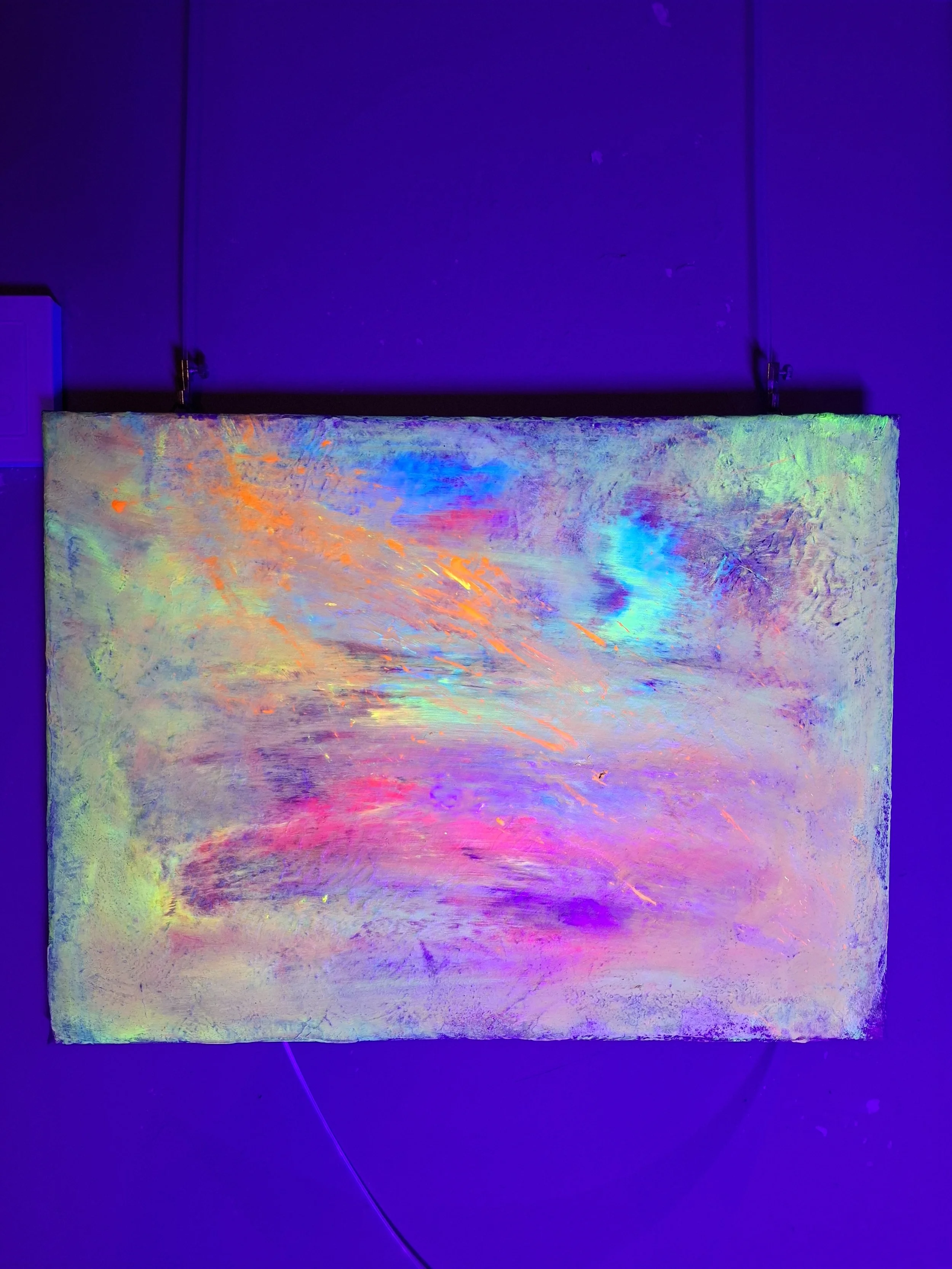 Ein leuchtendes, abstraktes Kunstwerk mit bunten, fließenden Farbmustern auf einer Leinwand, die im Dunkeln unter Schwarzlicht leuchtet.