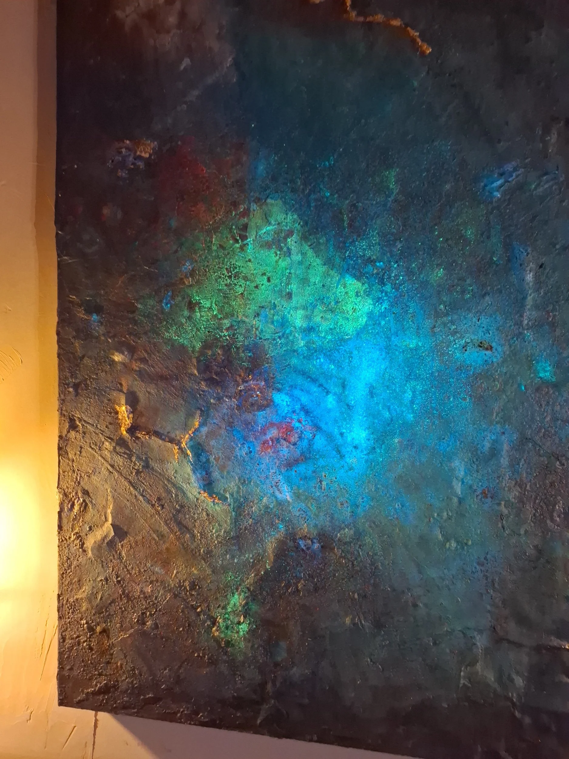 Ein Leinwandbild mit einer nächtlichen Szene in einer Höhle, leuchtende bunte Lichter reflektieren auf der dunklen, felsigen Oberfläche.