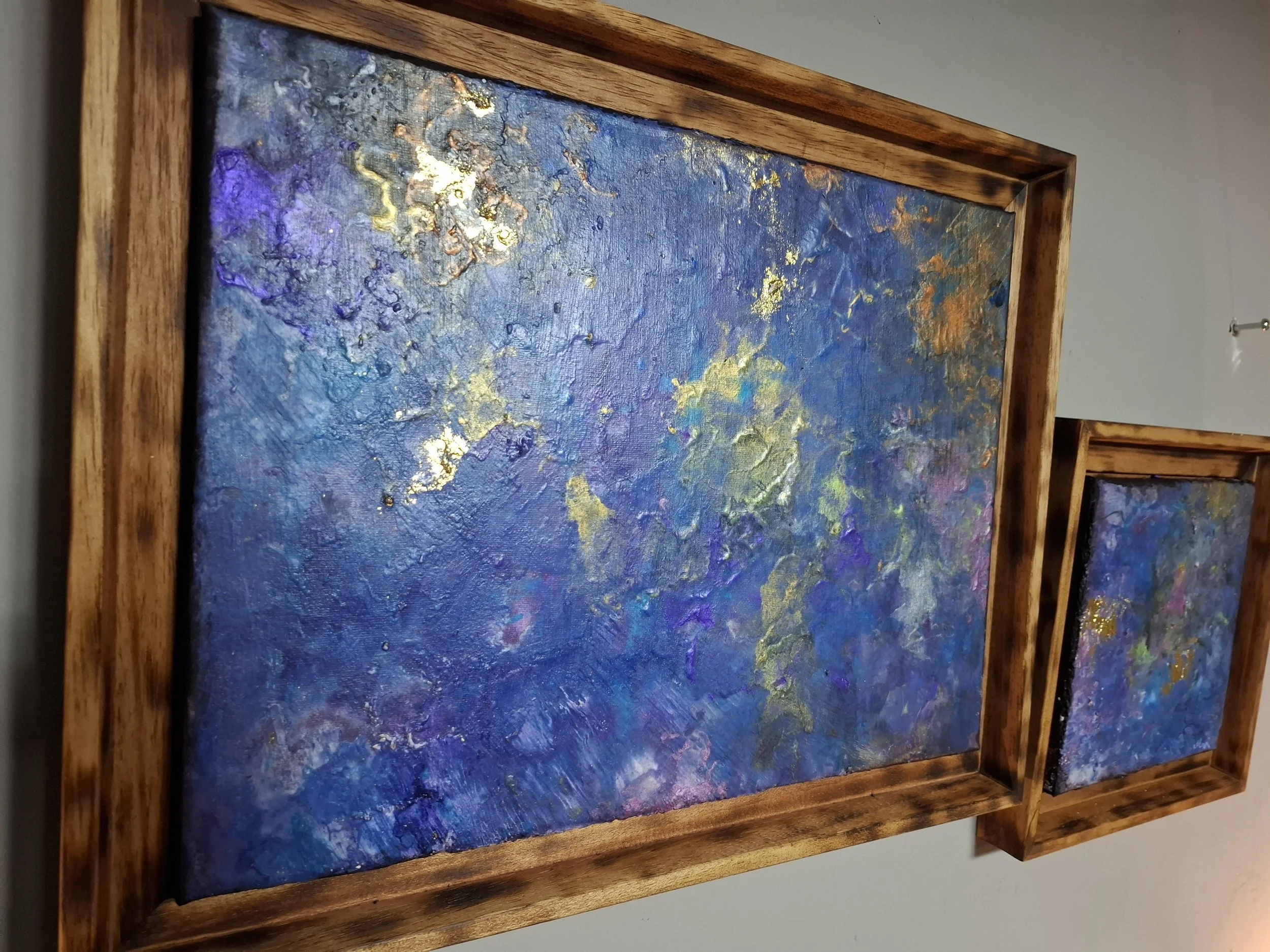 Abstraktes Gemälde mit blauen, goldenen und violetten Akzenten in Holzrahmen.