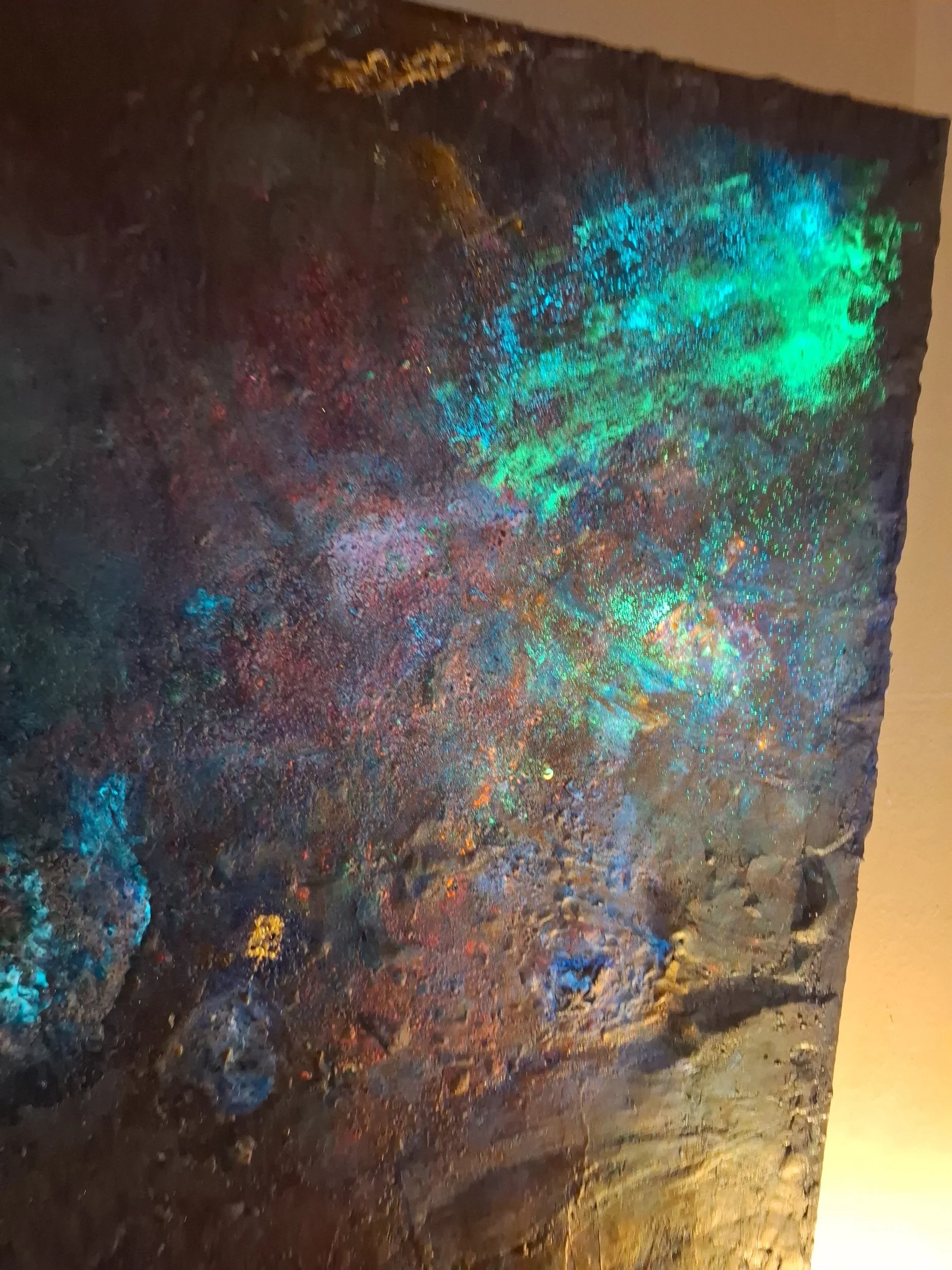 Ein Felsen mit bunten, schimmernden Mineralien und Edelsteinen, der im Licht leuchtet.