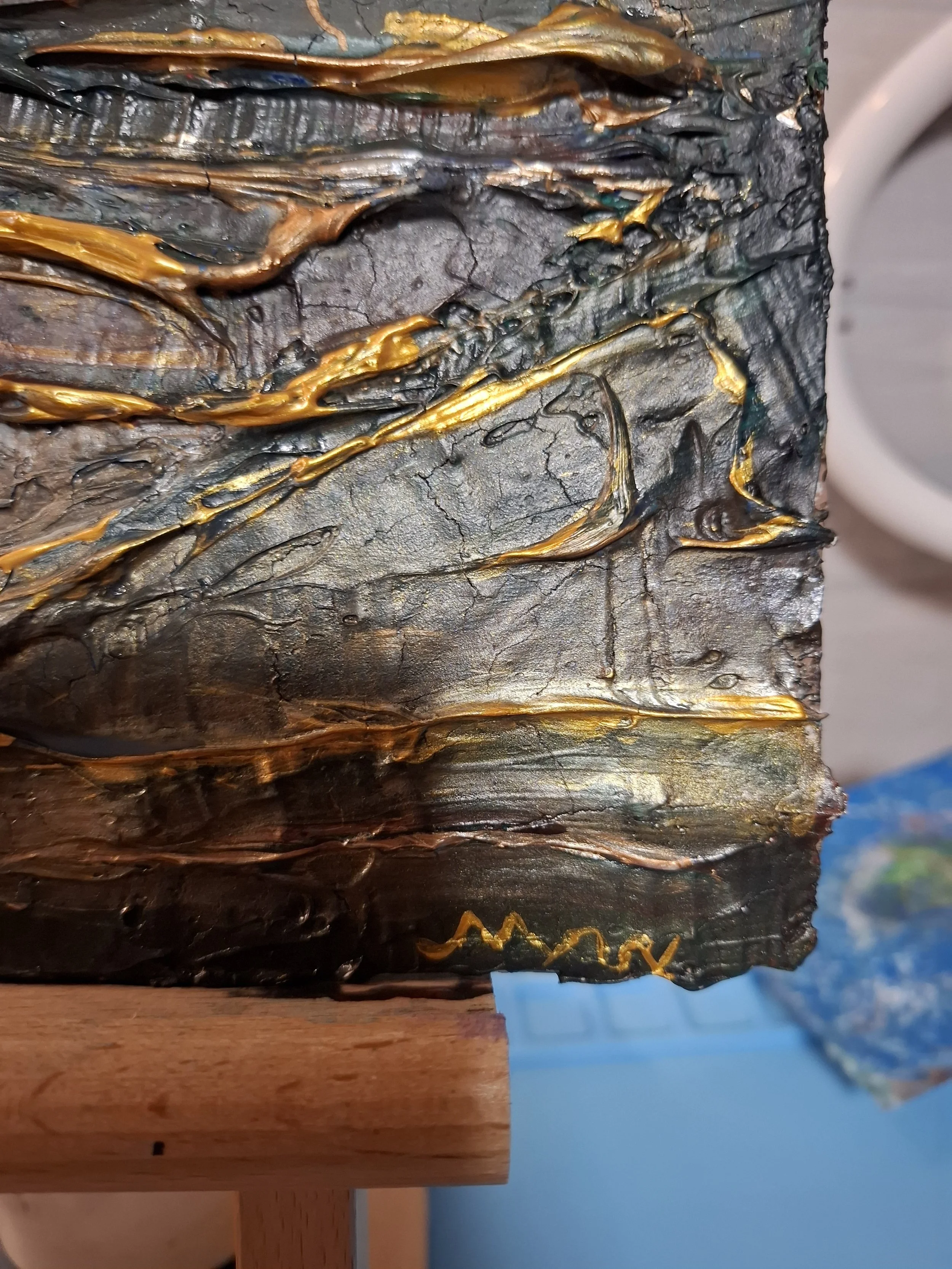 Eine Nahaufnahme einer künstlerischen piece, bestehend aus dick aufgetragenen, farbigen Materialschichten in Gold, Schwarz und Grau, die texturierte und strukturierte Oberfläche haben.