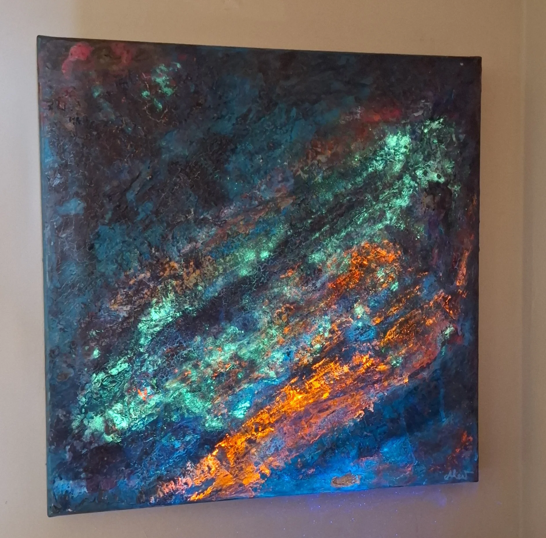 Ein abstrakes, farbenfrohes Gemälde mit leuchtenden, Metallic-Tönen, das auf einer Wand hängt.