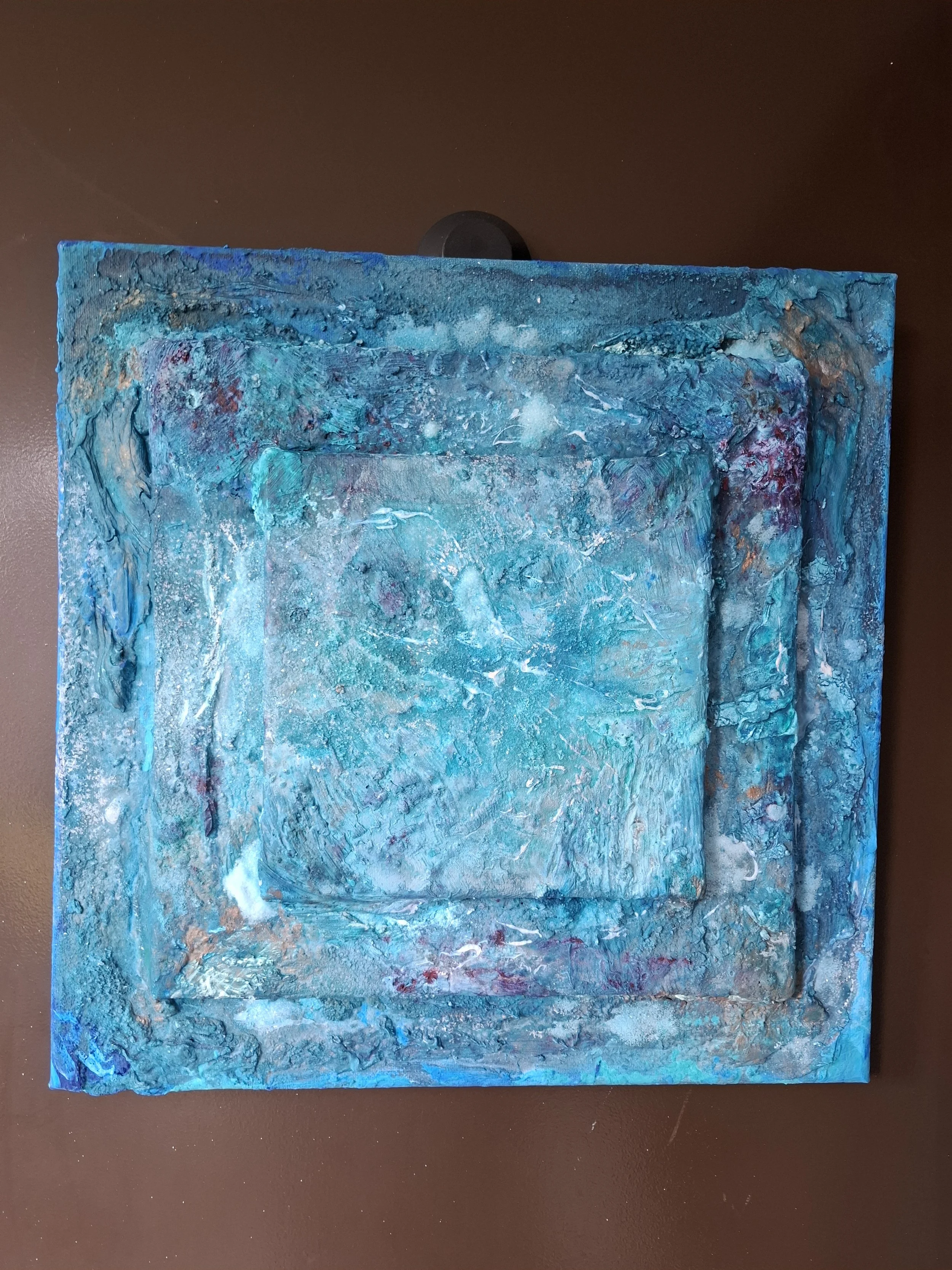 Abstraktes Kunstwerk mit verschiedenen Blautönen und Texturen auf einer Leinwand.