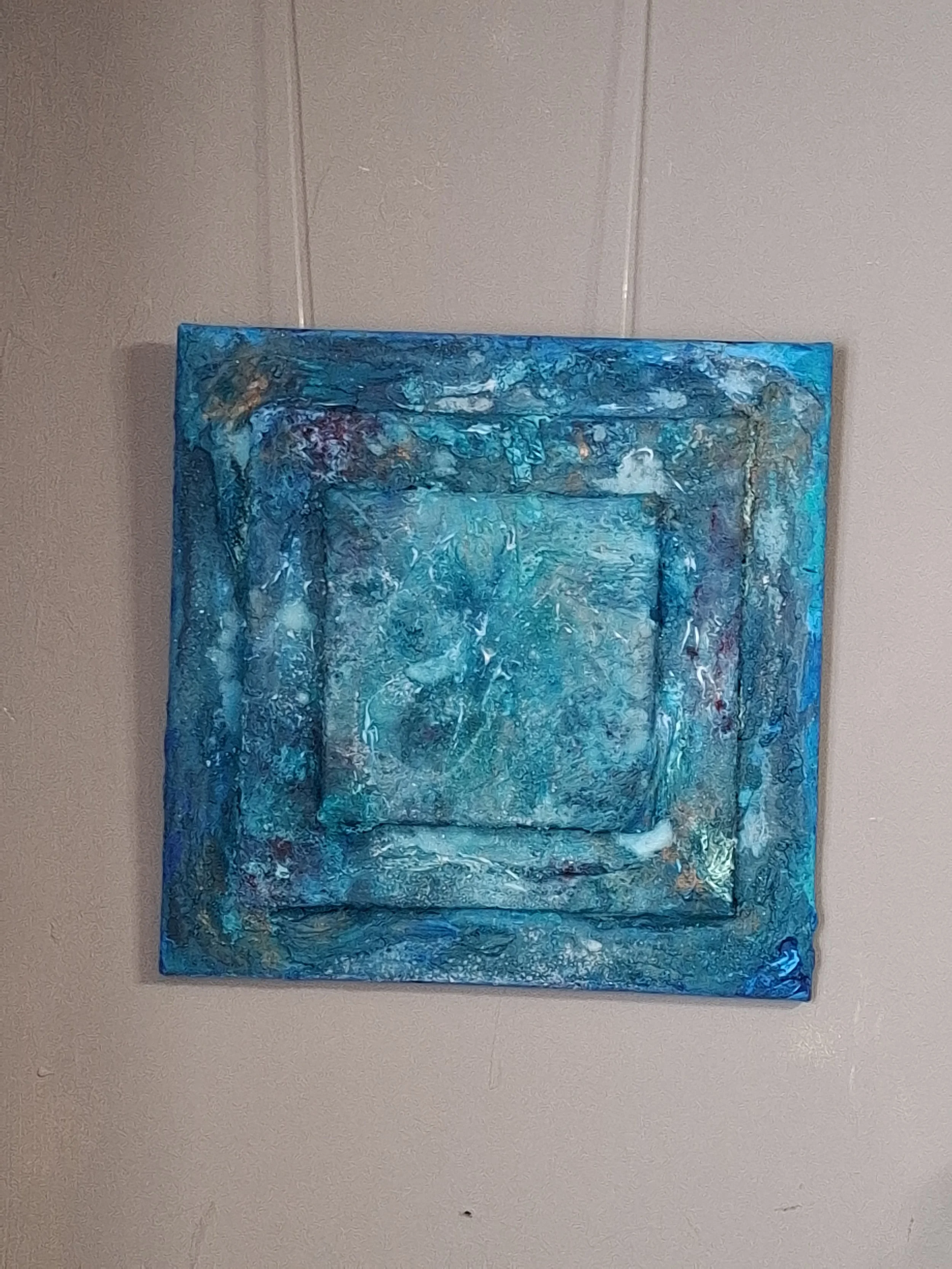 Abstraktes Gemälde in Blautönen hängt an einer grauen Wand.