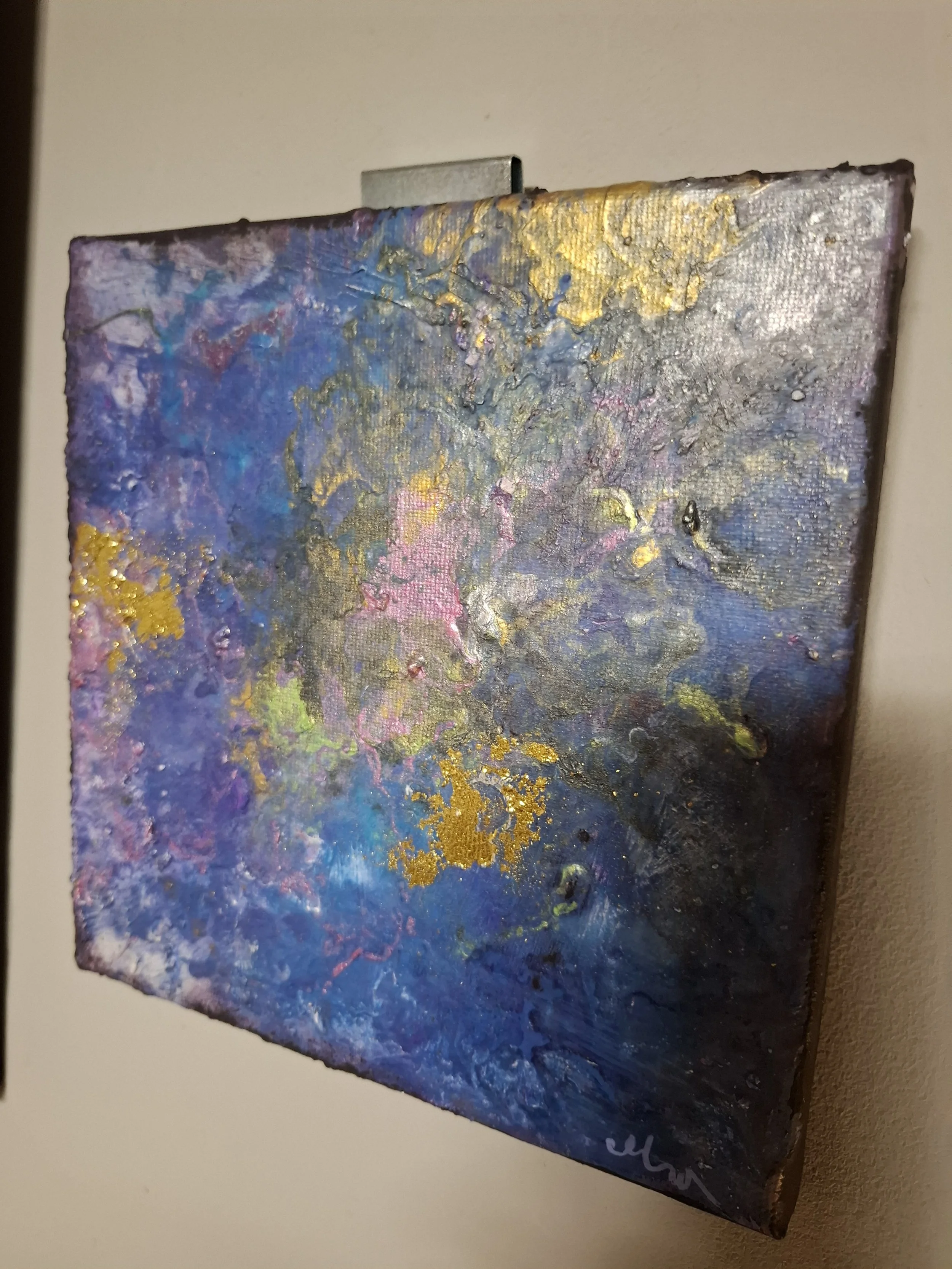 Abstraktes Gemälde mit Farben in Blau, Gold, Pink, Grün und Lila, mit strukturierten Texturen andüten, auf einer weißen Wand