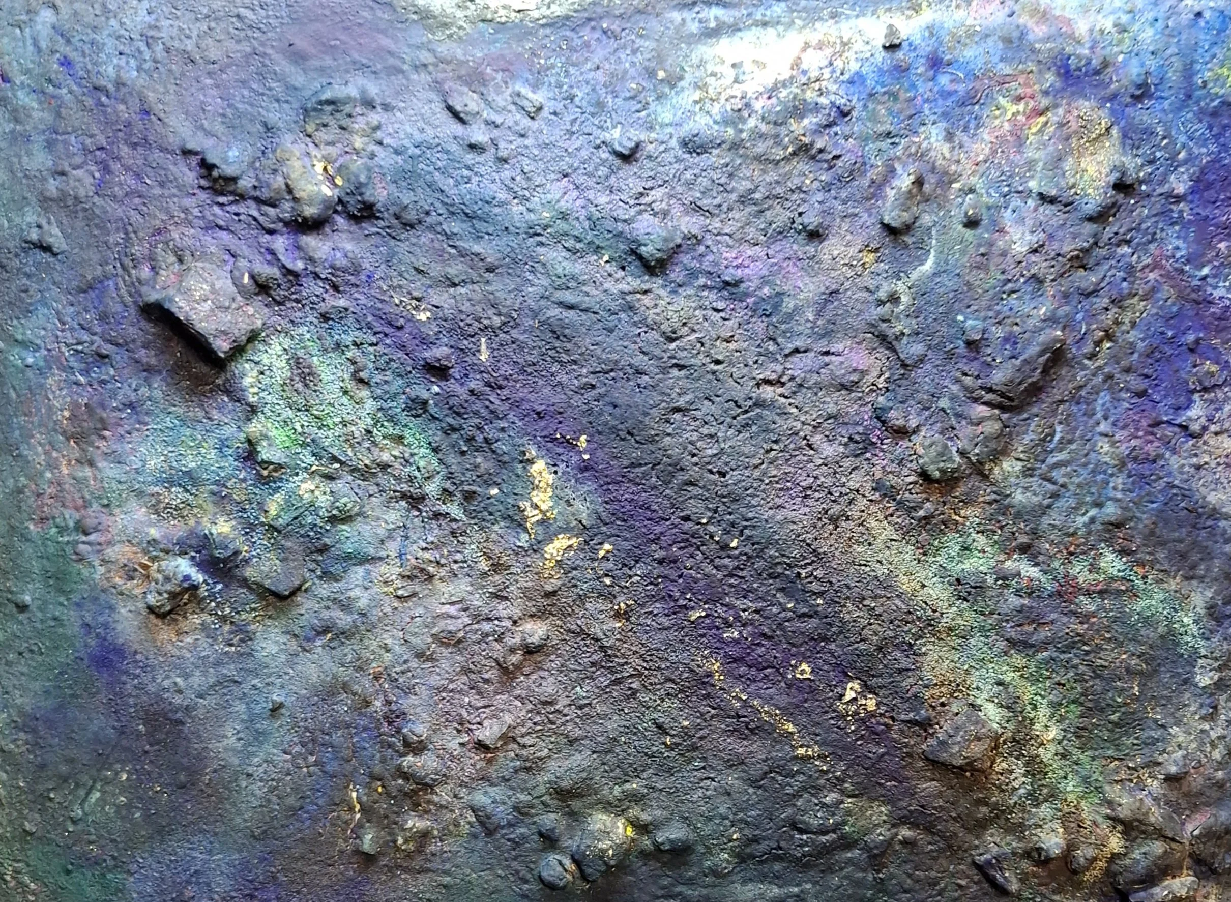 Nahaufnahme von buntem Staub und Mineralien mit schillernden Farben auf einer Oberfläche.