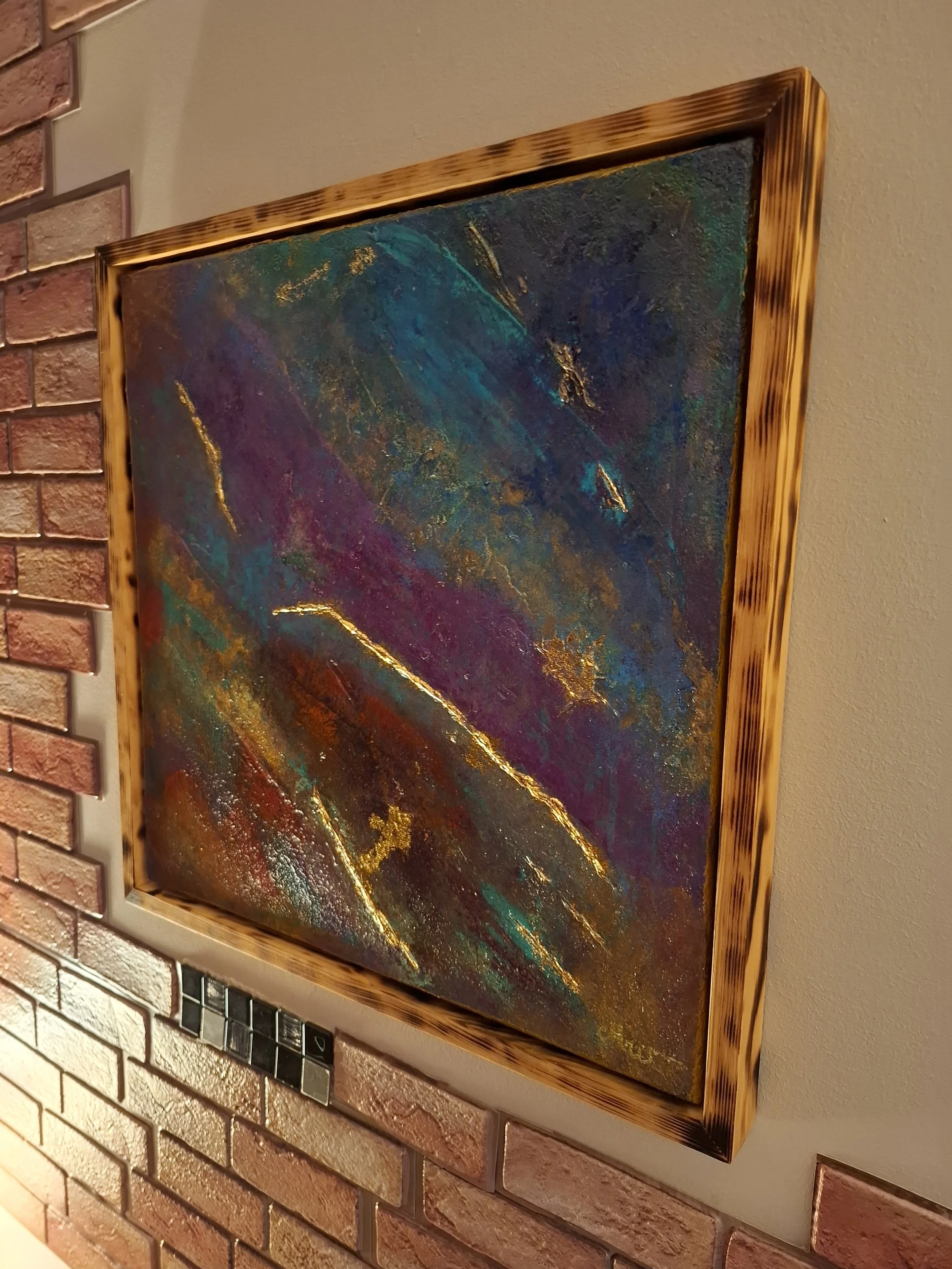 Abstraktes Gemälde mit bunten, goldenen Akzenten, in einer goldgestreiften Holzrahmen. Schon auf der Wand angebracht.