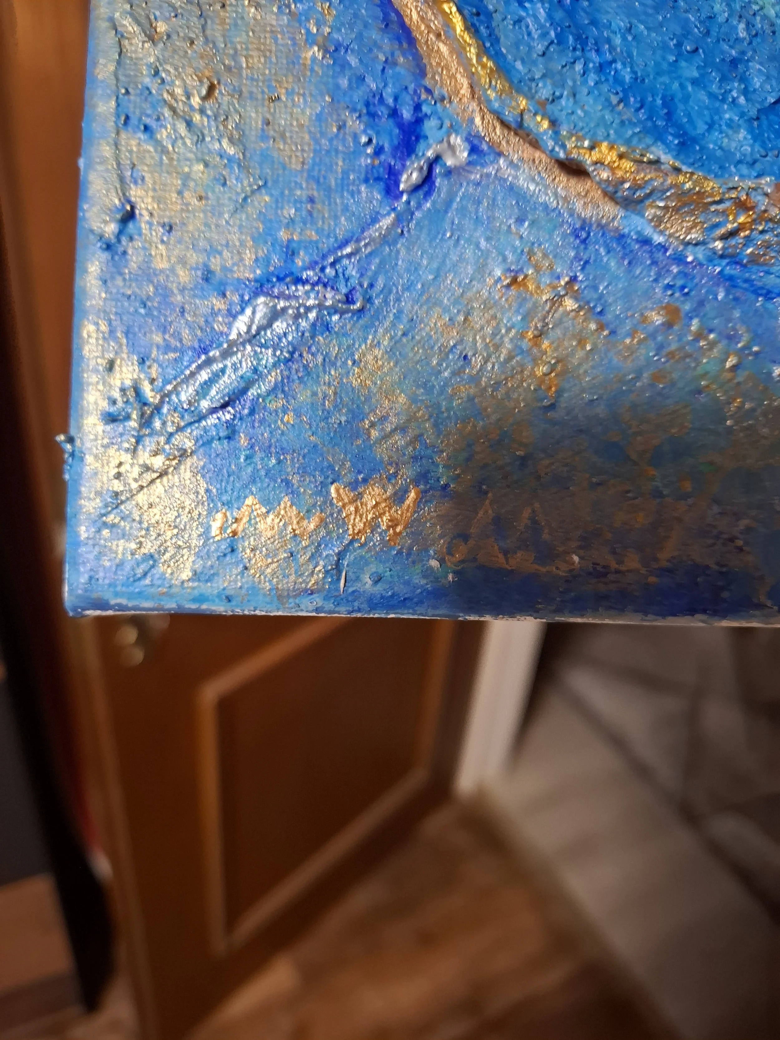 Ein Detailfoto eines buntenGemäldes mit blauen, goldenen und silbernen Akzenten, im unteren Bereich ist eine zackige goldene Linie zu sehen.