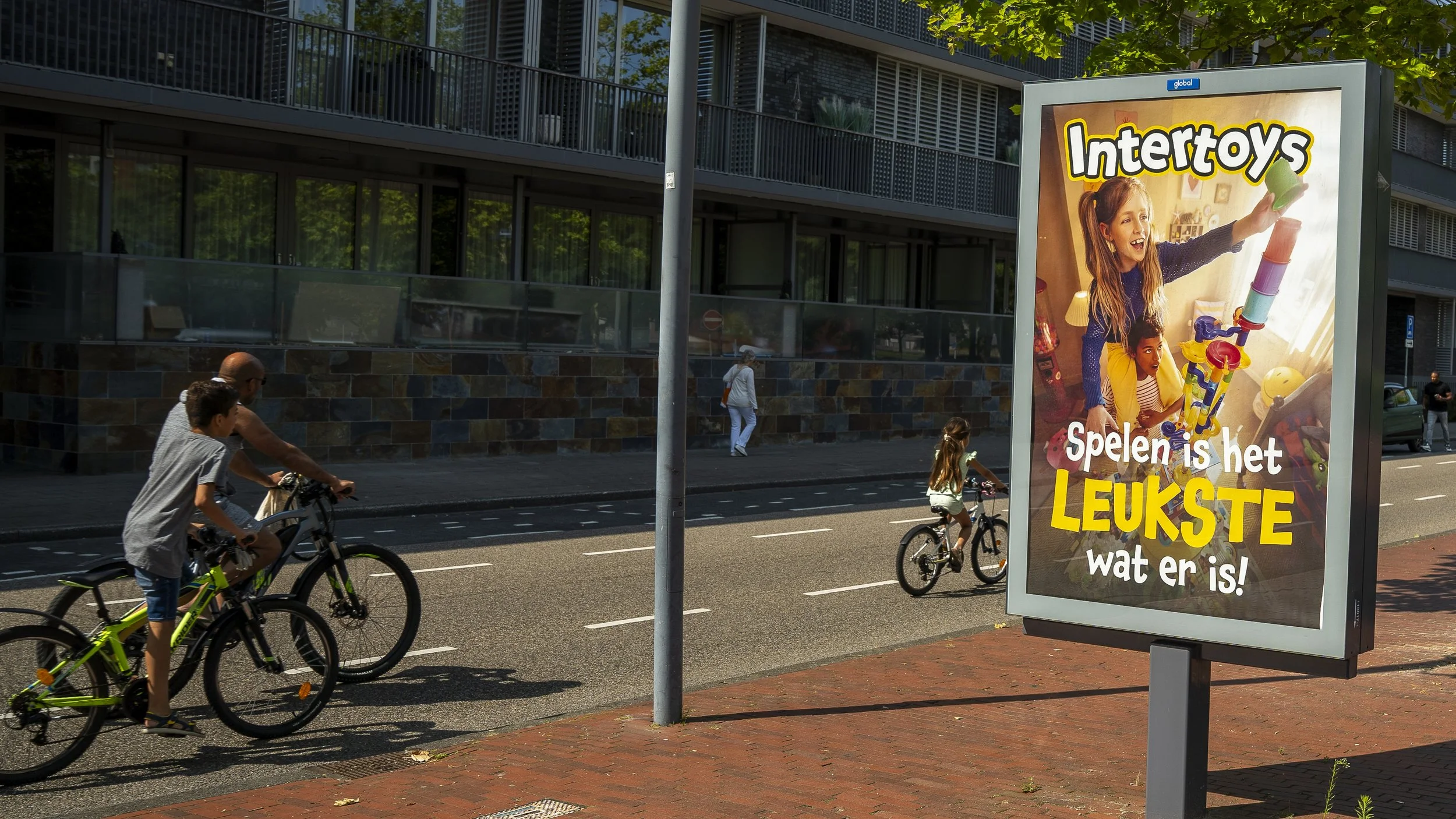 A billboard advertisement for Intertoys featuring children playing with a building toy set inside a room, with text in Dutch that says 'Spelen is het leukste wat er is!'