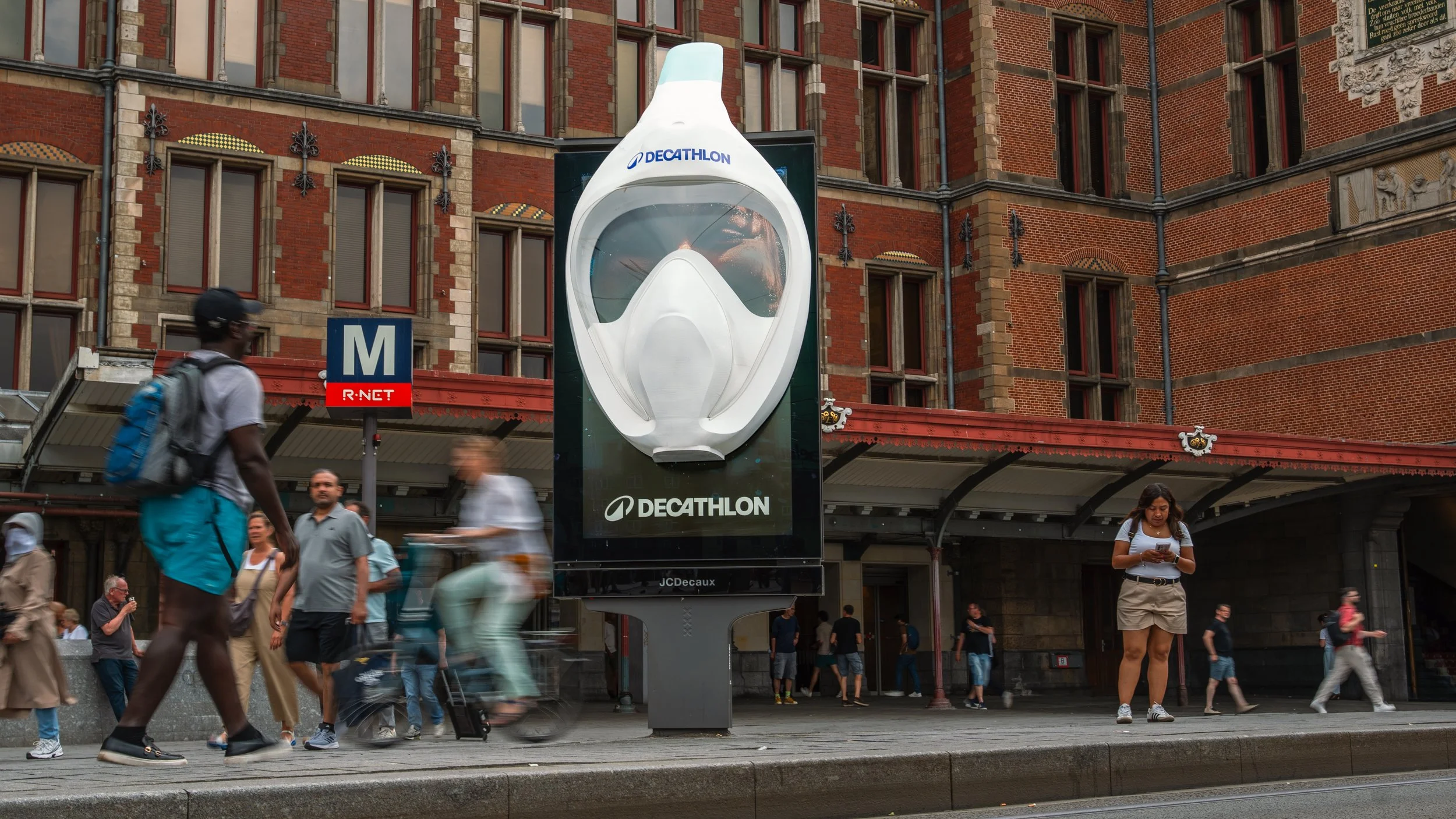 Straat met mensen en een grote advertentie met een snorkelmasker en het logo van Decathlon.