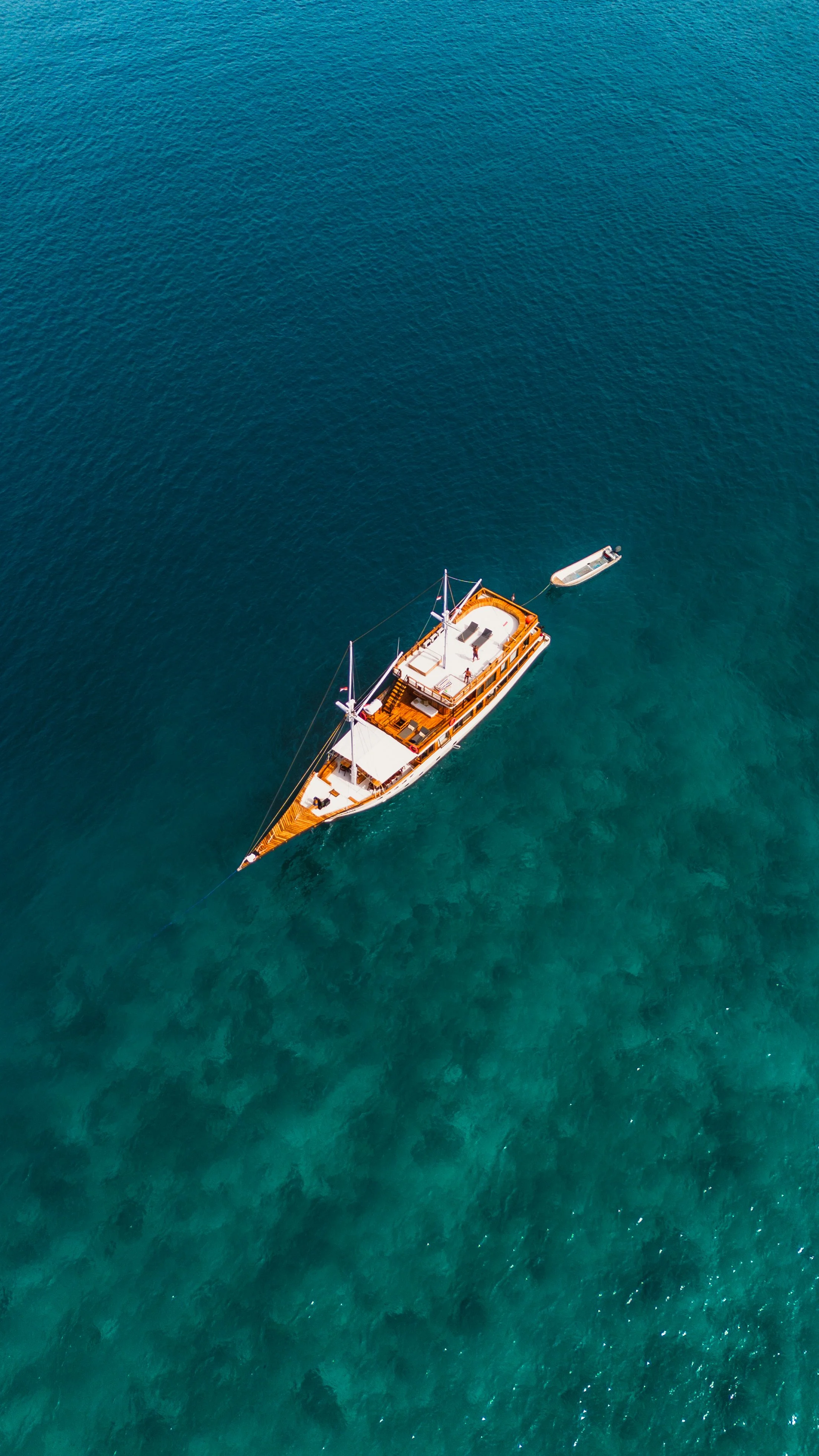 Een drijvende houten boot op de zee met een kleine sloep naast zich