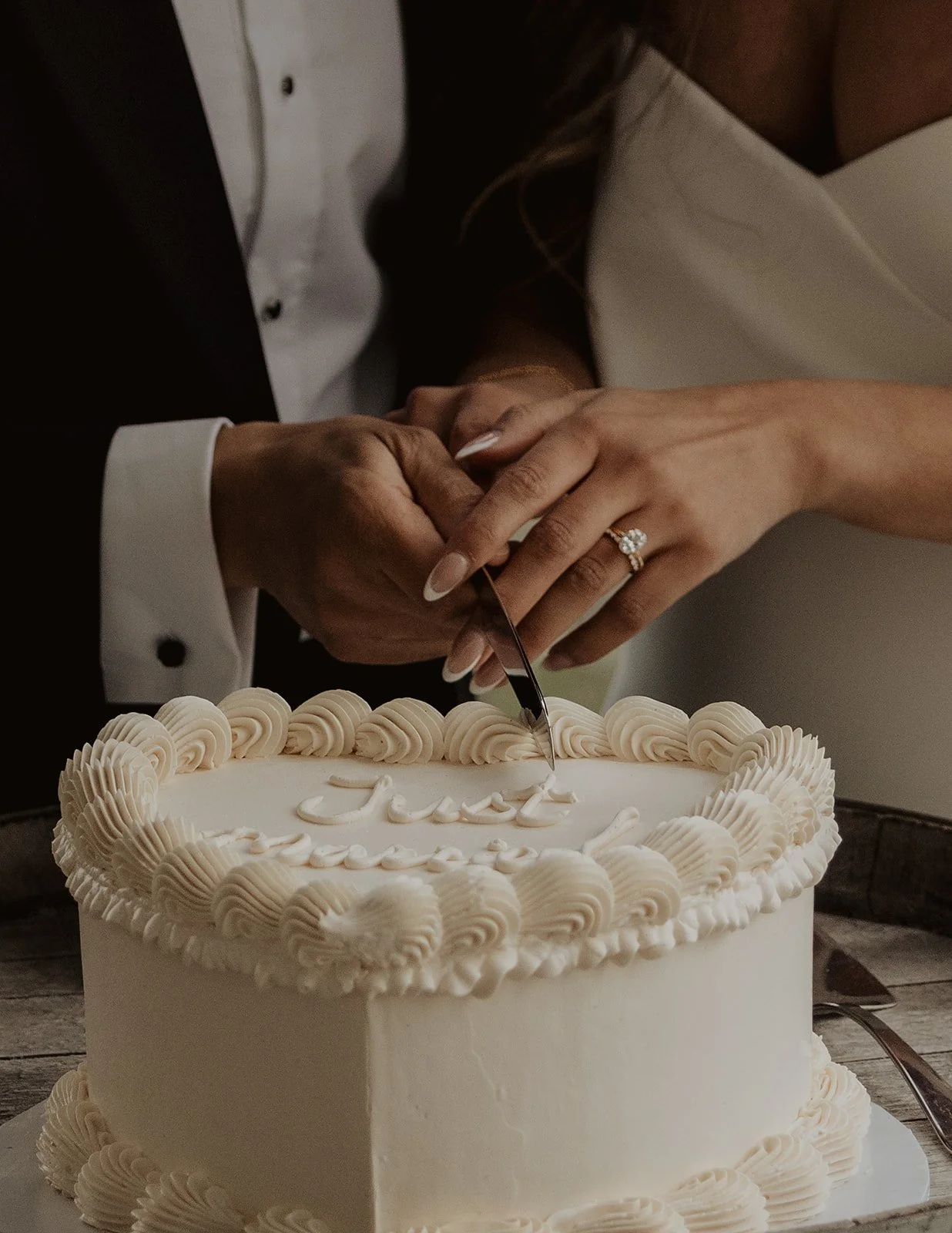 Couple cutting wedding cake together during reception captured by Kelowna wedding photographer Jordana Dickson