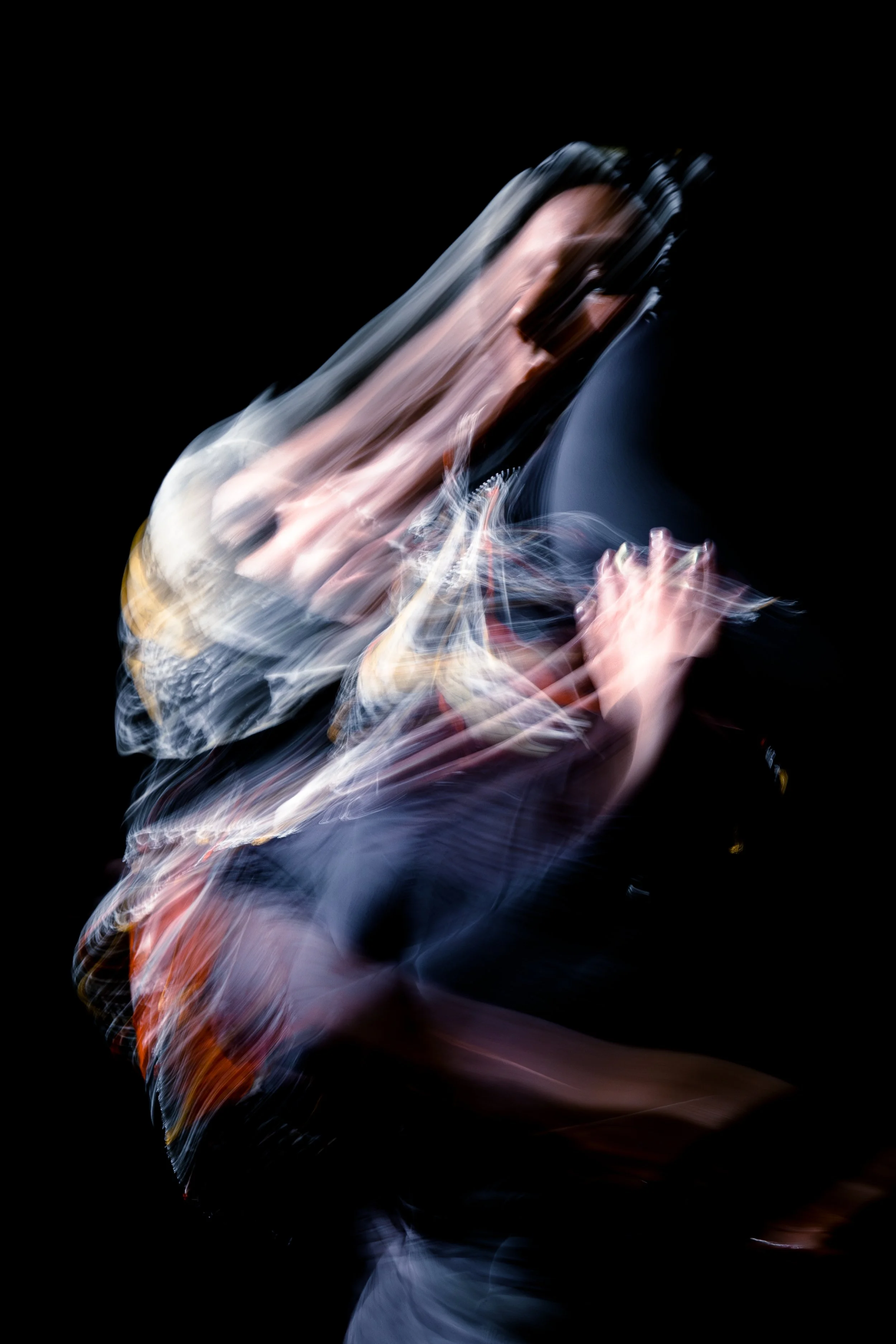 Abstract blurred image with swirling colors of black, white, red, and blue against a black background.