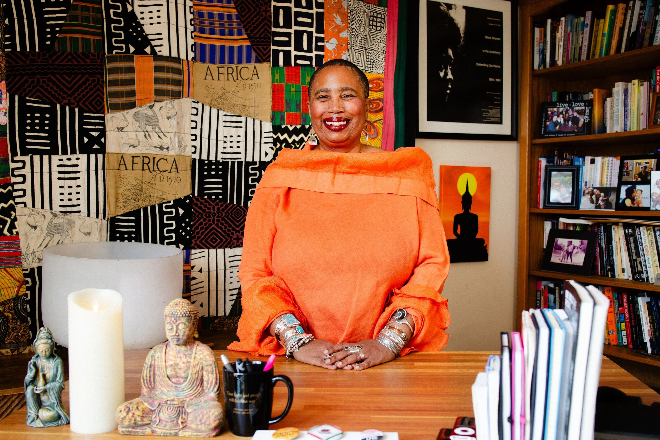 Aishah Shahidah Simmons at her desk, African textiles behind her, Buddhist figurines nearby. Photo by Studio TSHAY.